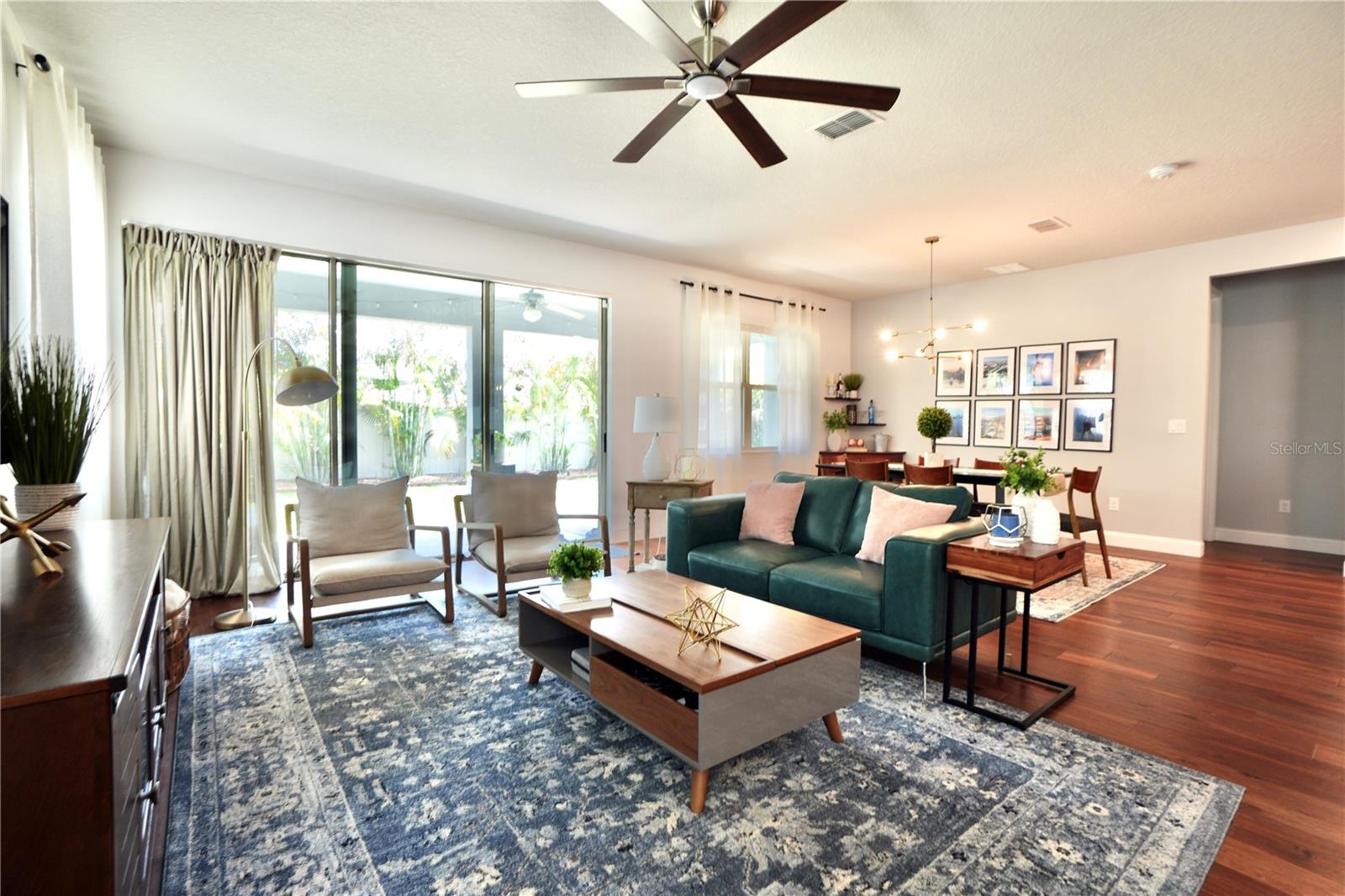 Open, light and bright great room with wood floors, ceiling fan and triple sliding doors to the covered lanai.