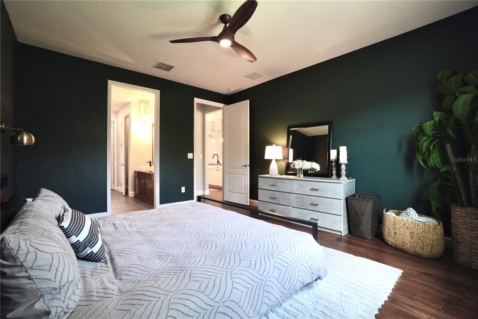 Primary bedroom with wood floors and ceiling fan.