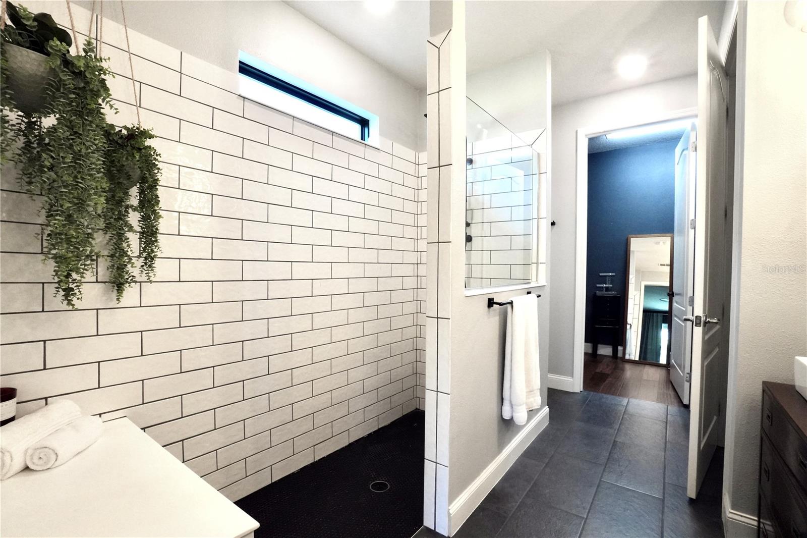 Large walk-in shower with upgraded tile walls and floors and built-in shower bench. Linen closet located to the left of the walk-in closet.