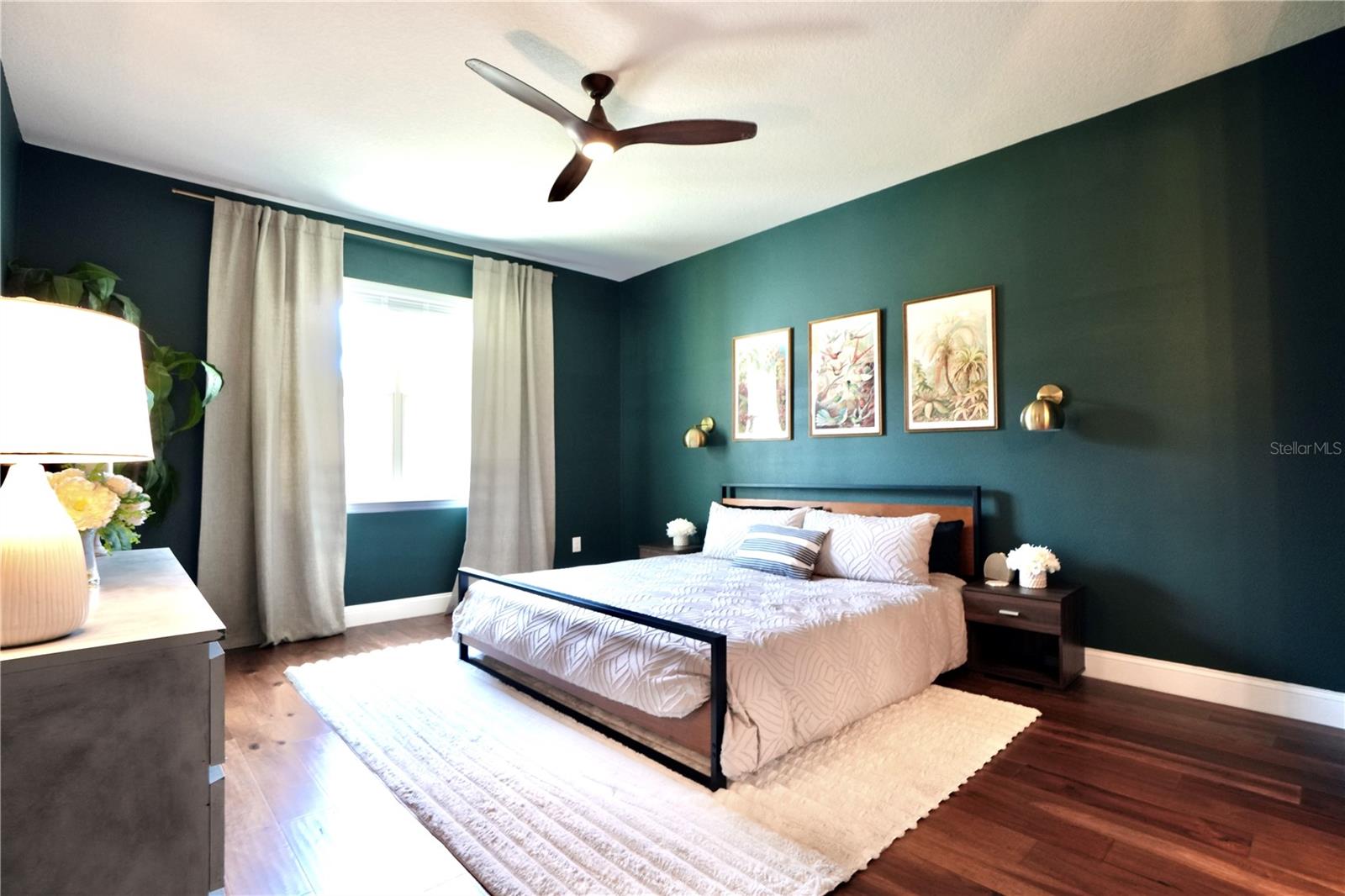 Spacious primary en-suite with wood floors and ceiling fan.