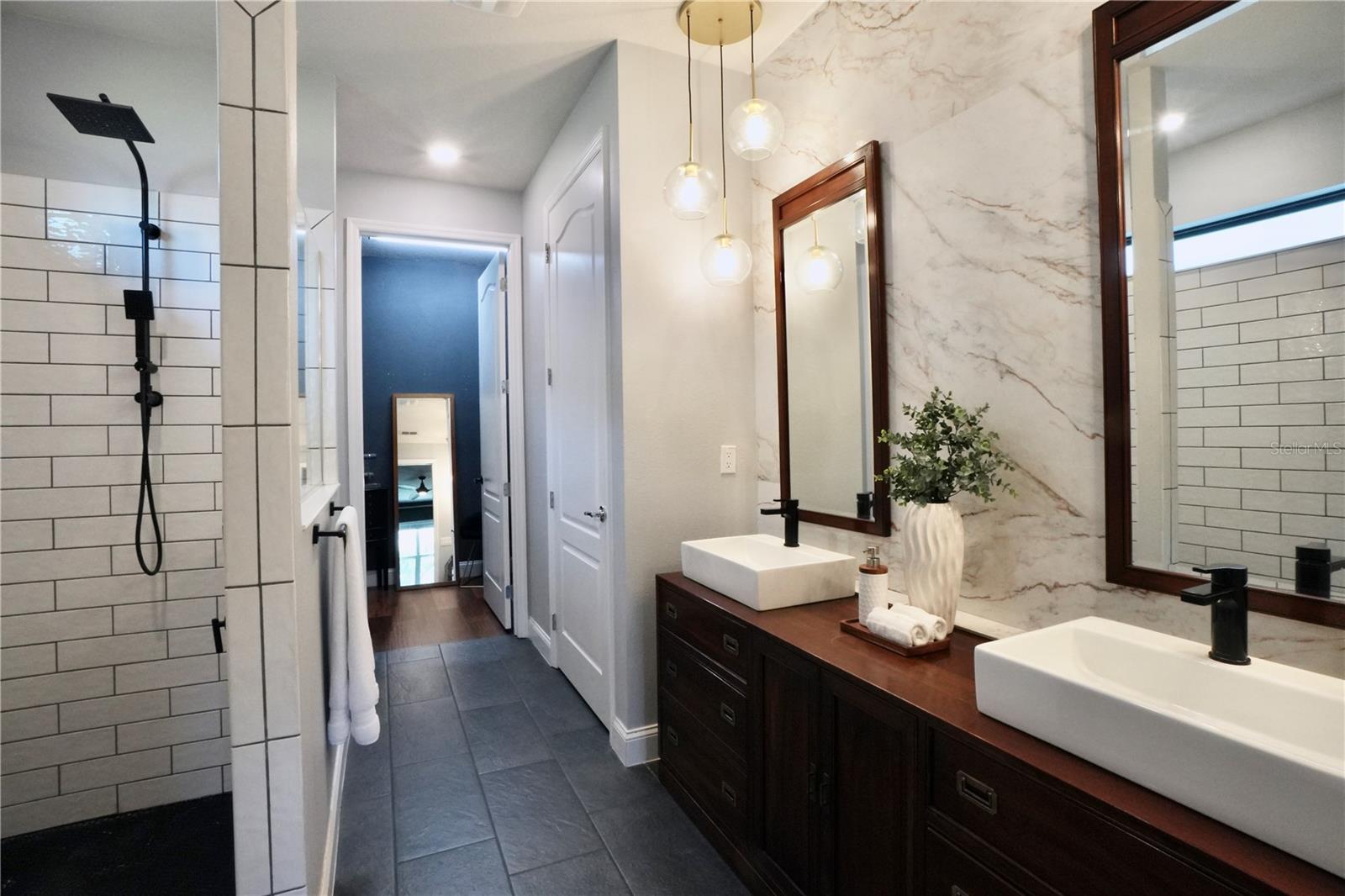 Primary en-suite bathroom with tile floors, walk-in shower, double sink vanity, walk-in closet and private water closet.