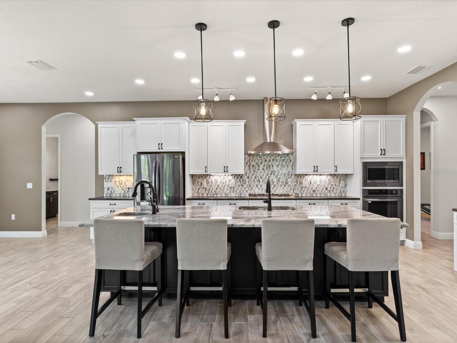 A beautiful chef’s kitchen showcases a Viking cooktop, elegant leather-finish granite countertops, and a striking granite breakfast island