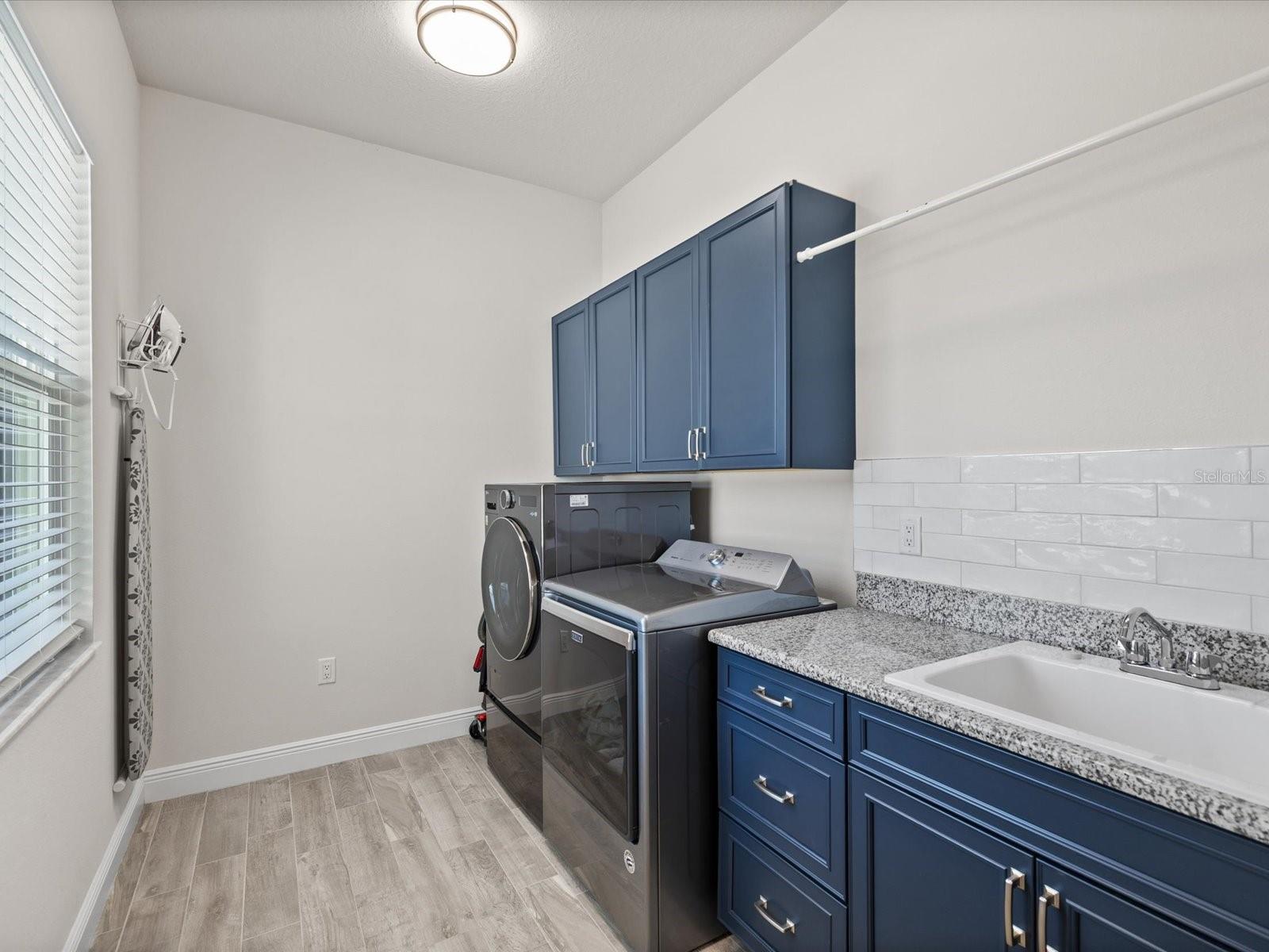 A light and bright laundry room featuring custom cabinets and thoughtful extras for everyday convenience.