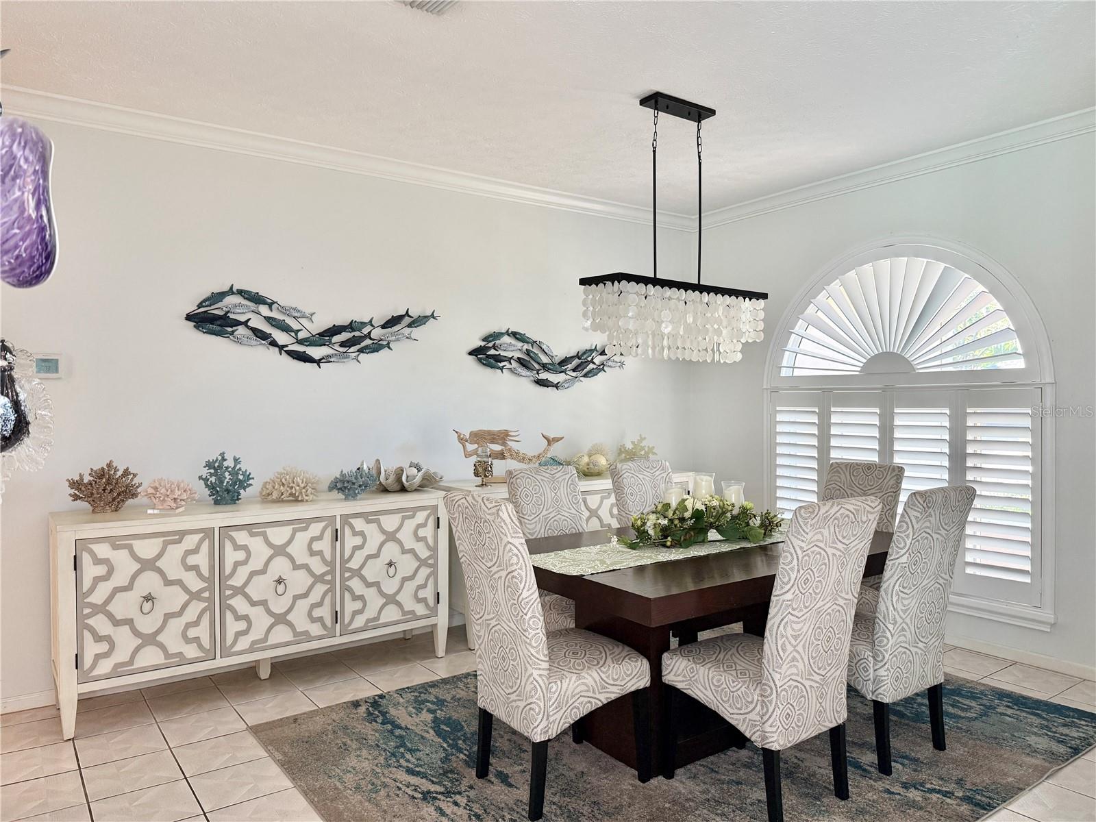 Formal Dining Space with Arched Window with decorative sunburst (fanlight) transom and plantation shutters