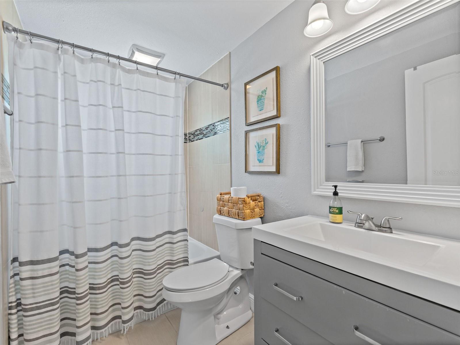 Hall bathroom with updated single sink vanity and updated fixtures and lighting