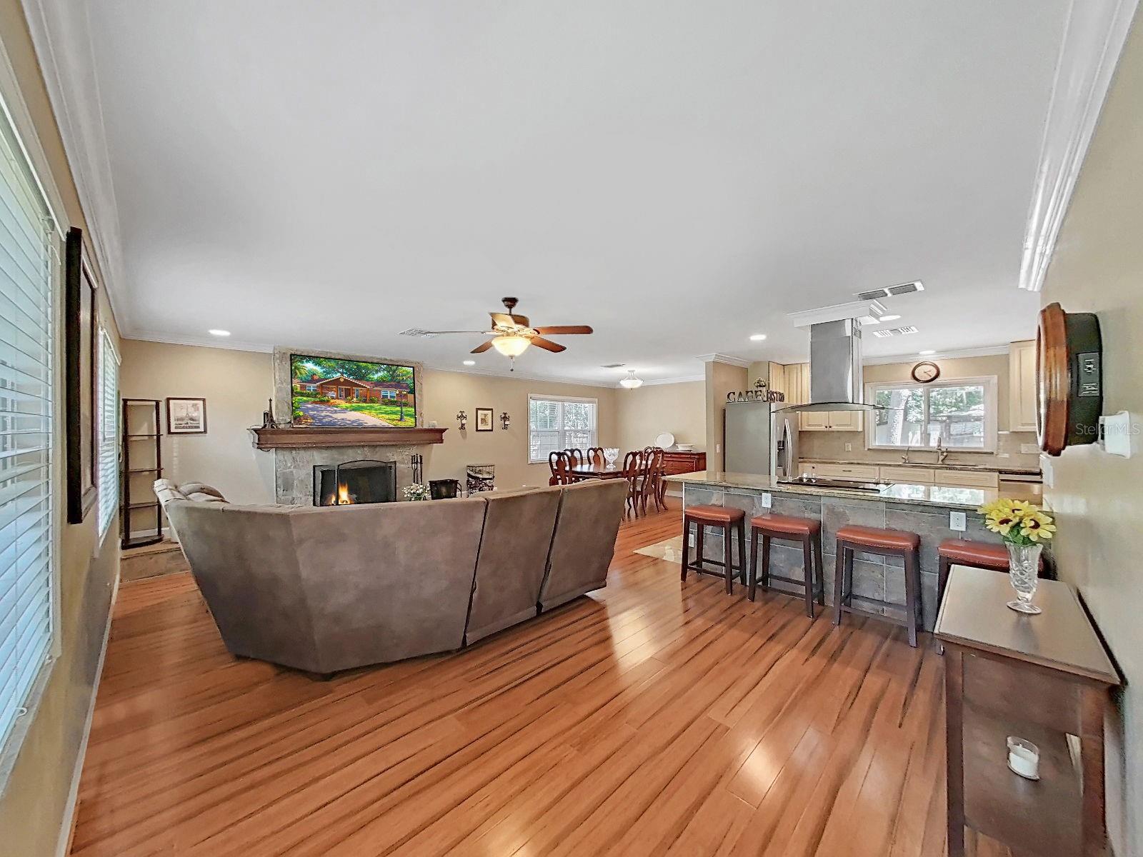 incredible open-concept Great Room with living area, wood-burning stone fireplace, dining room, and kitchen all flowing seamlessly together on gorgeous floors!