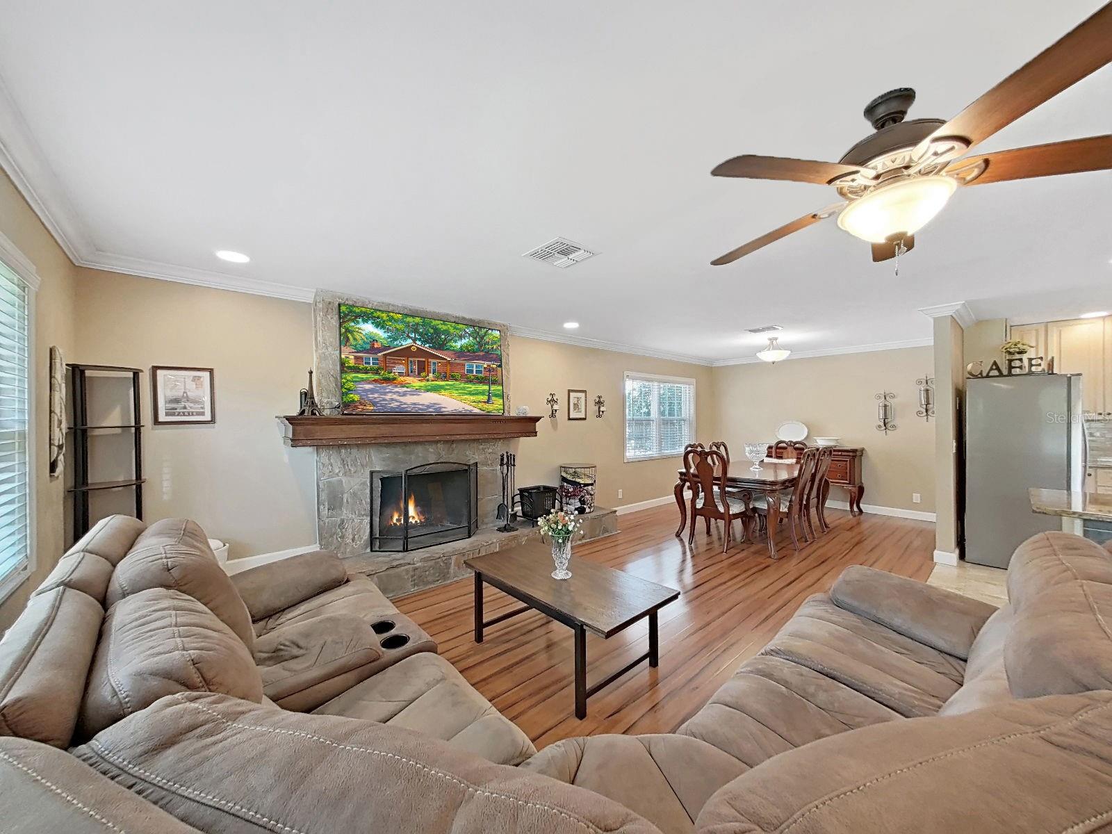 Spacious living room with cozy stone wood-burning fireplace, & open flow into the dining and kitchen areas.