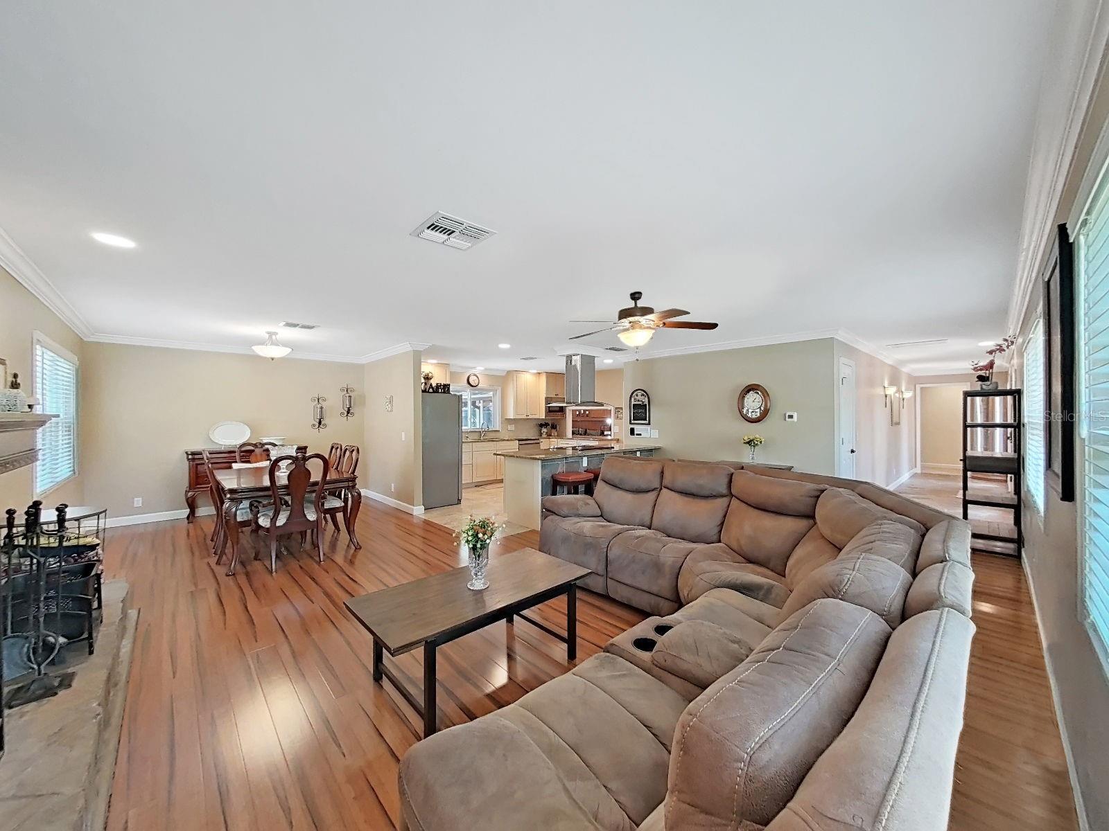 Panoramic view of the living, dining, & kitchen areas. The home's open layout & gleaming floors make it feel grand!