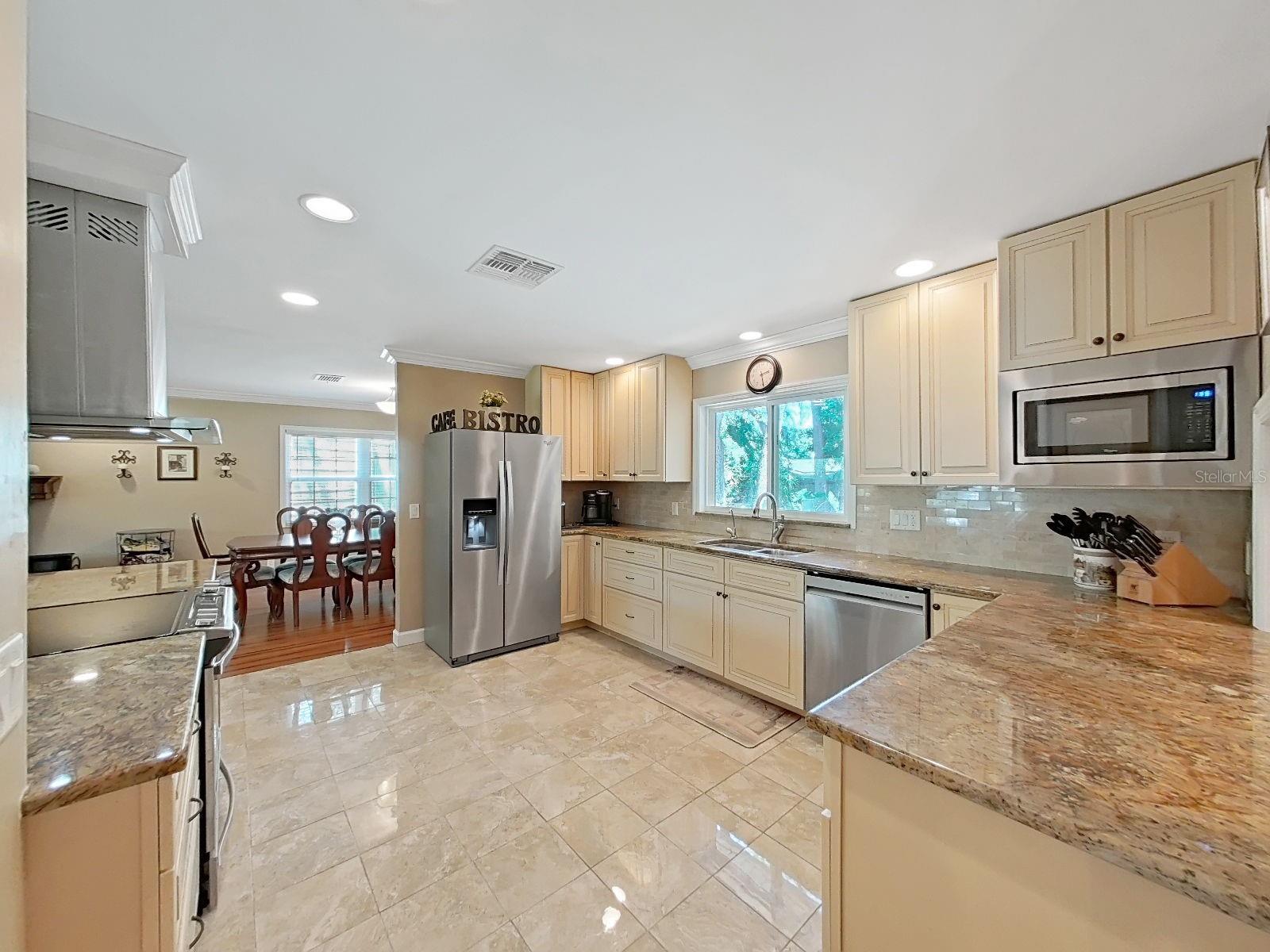 Beautiful, spacious kitchen with abundant cabinetry, granite counters, stainless appliances, tile backsplash, & views into the dining room, living room, & bonus game room. Also, greenery views of the relaxing backyard. This is the hub of the home!