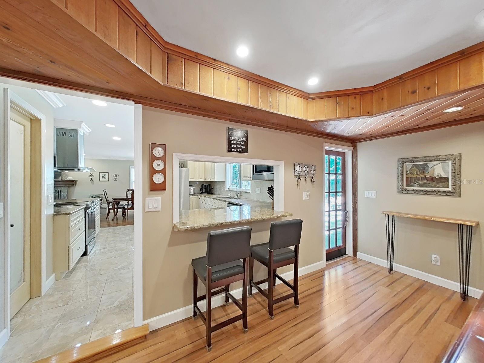 Unique pass-through bar, connecting the Kitchen to the Bonus Game Room- a home entertainer's dream detail! The french door leads to the side patio & backyard.