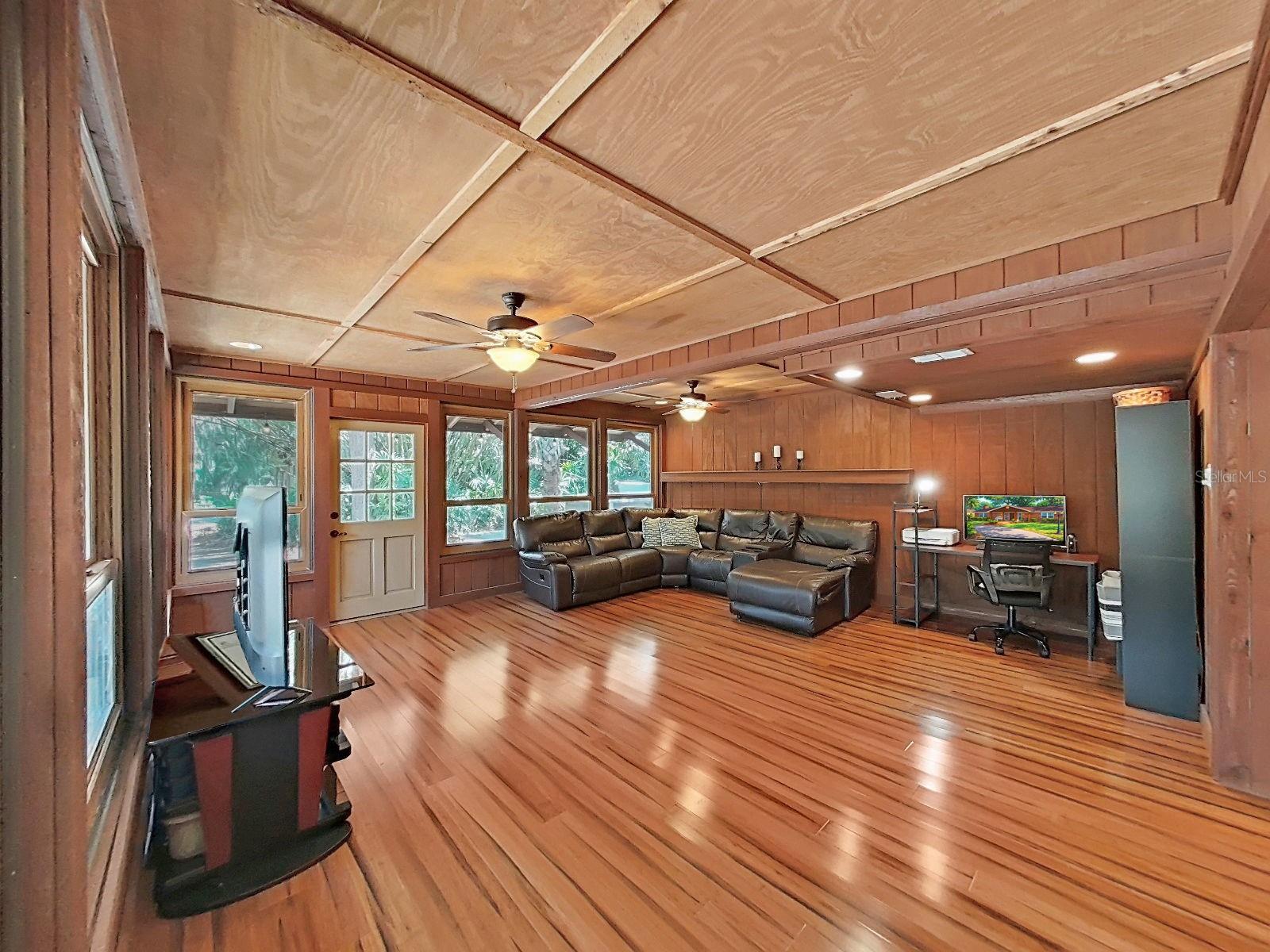 Family Room with warm wood details and a wall of newer windows, offering peaceful views and vibes of the resort-style backyard. A truly versatile and welcoming space to gather, lounge, and relax.