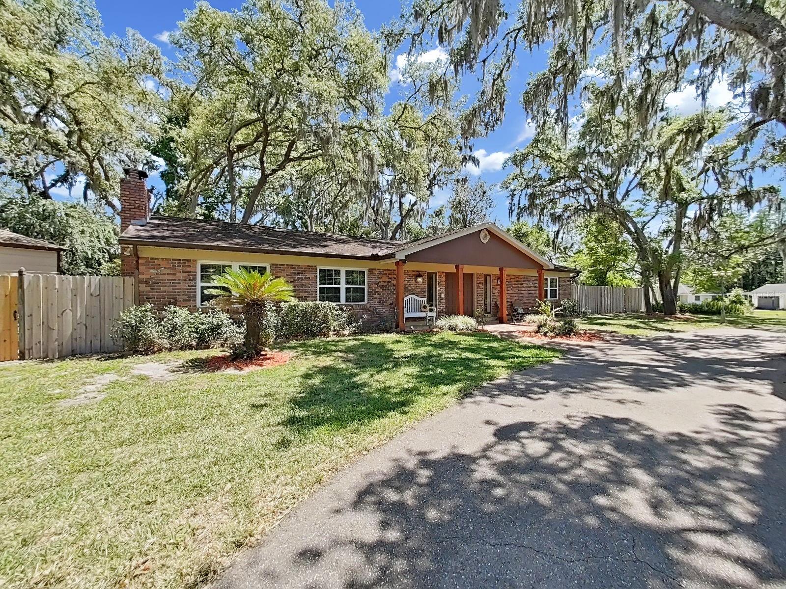 View from the circular driveway, showcasing the sprawling ranch style home on over a half-acre lot with privacy fencing.