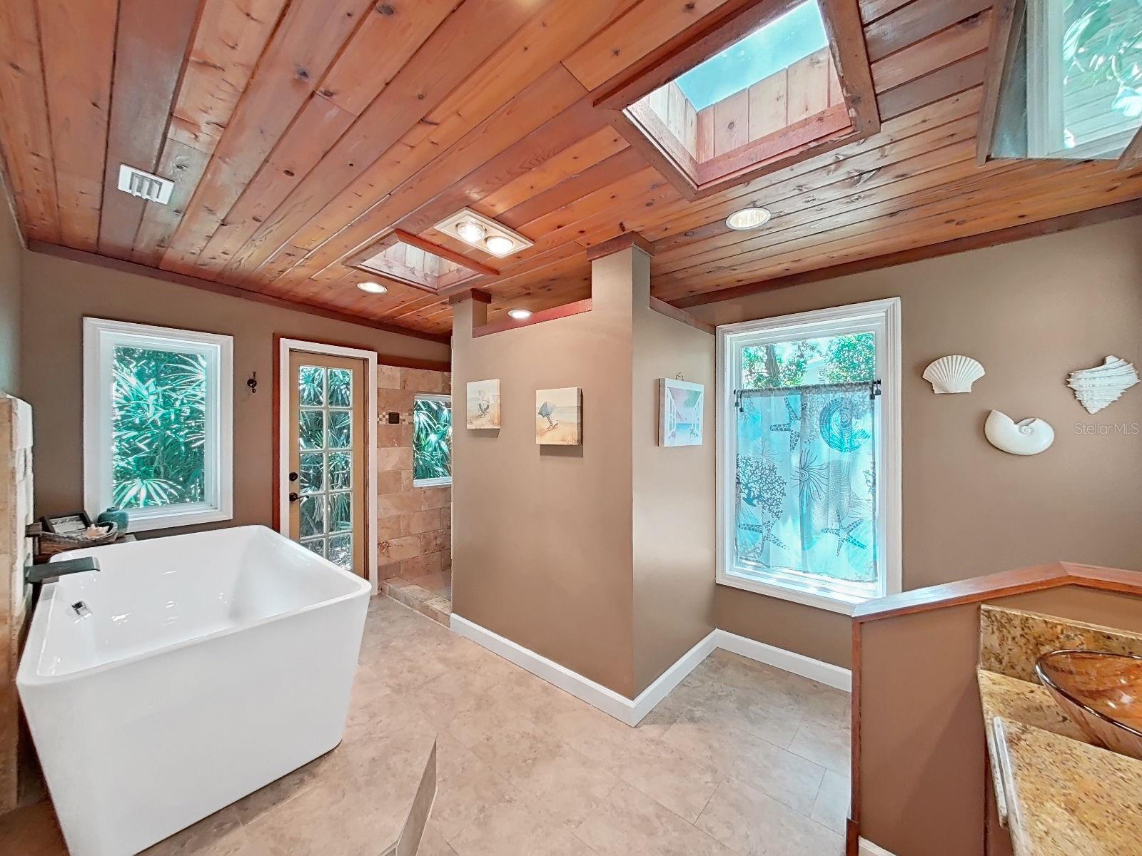 Stunning primary bath with freestanding soaking tub, skylights, french-door to the outdoors, and dual vessel sinks set in a large vanity. An absolute spa sanctuary!