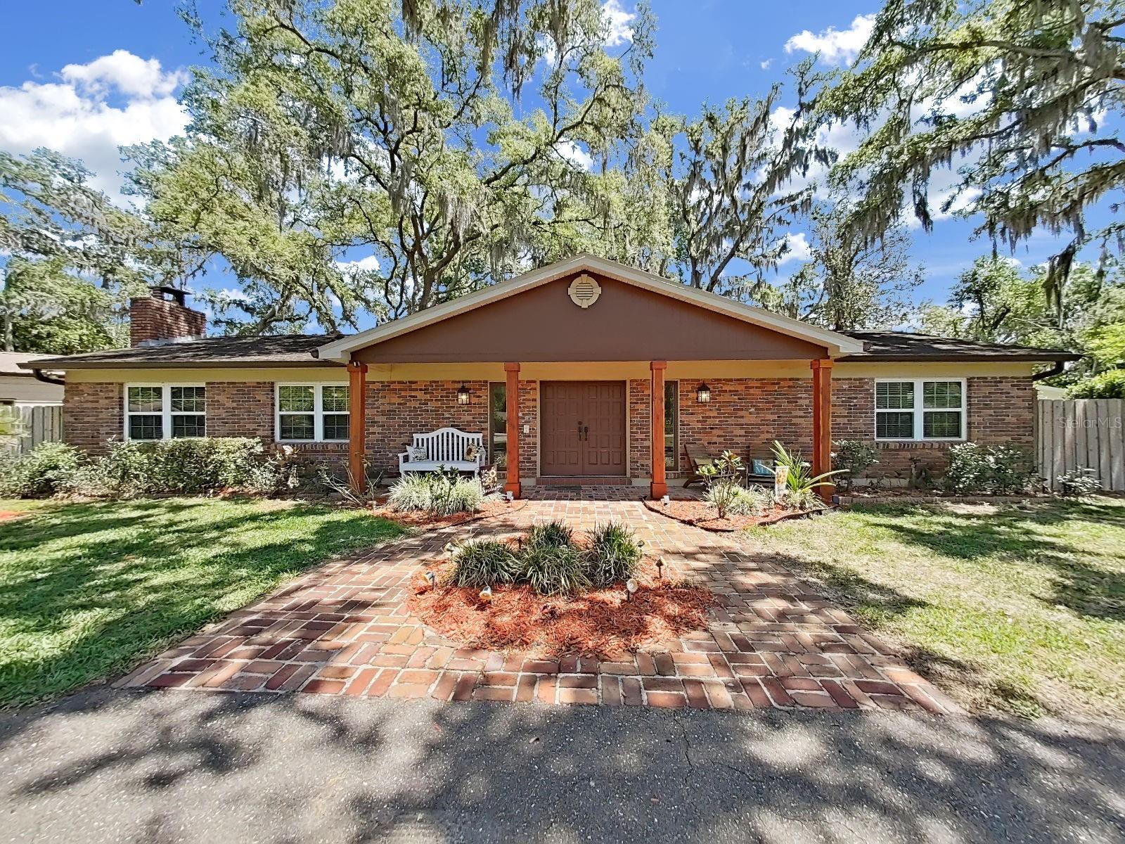 Lovely front elevation with brick paver courtyard, wood beam covered entry and stunning backdrop of mature trees. Curb appeal at its finest!