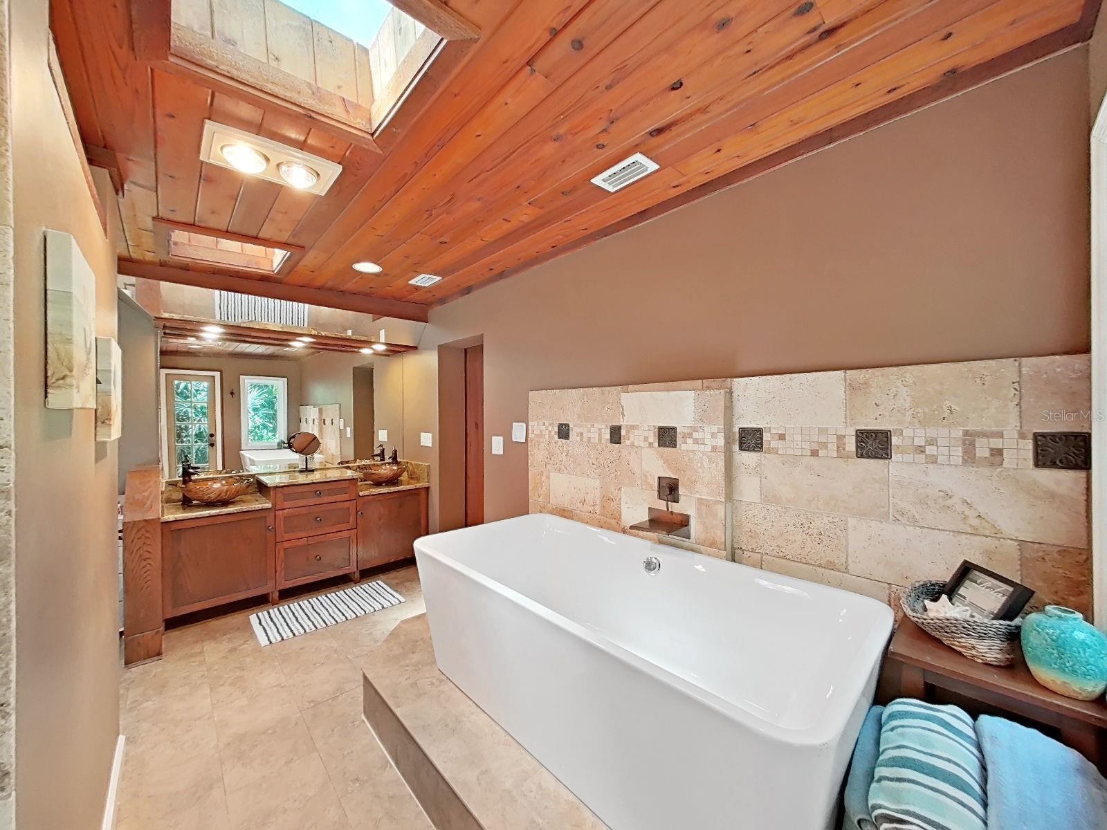 Primary Bath that rivals any luxury resort- soaking tub with tile surround, dual sinks, wood-planked ceiling with skylights, lots of natural light!