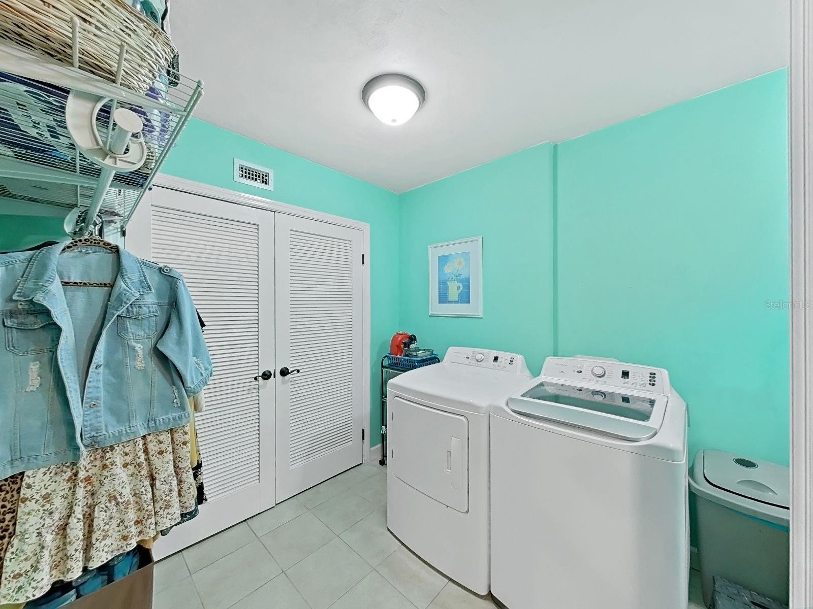 Cheerful and spacious laundry room with shelving & plenty of room for side-by-side appliances.