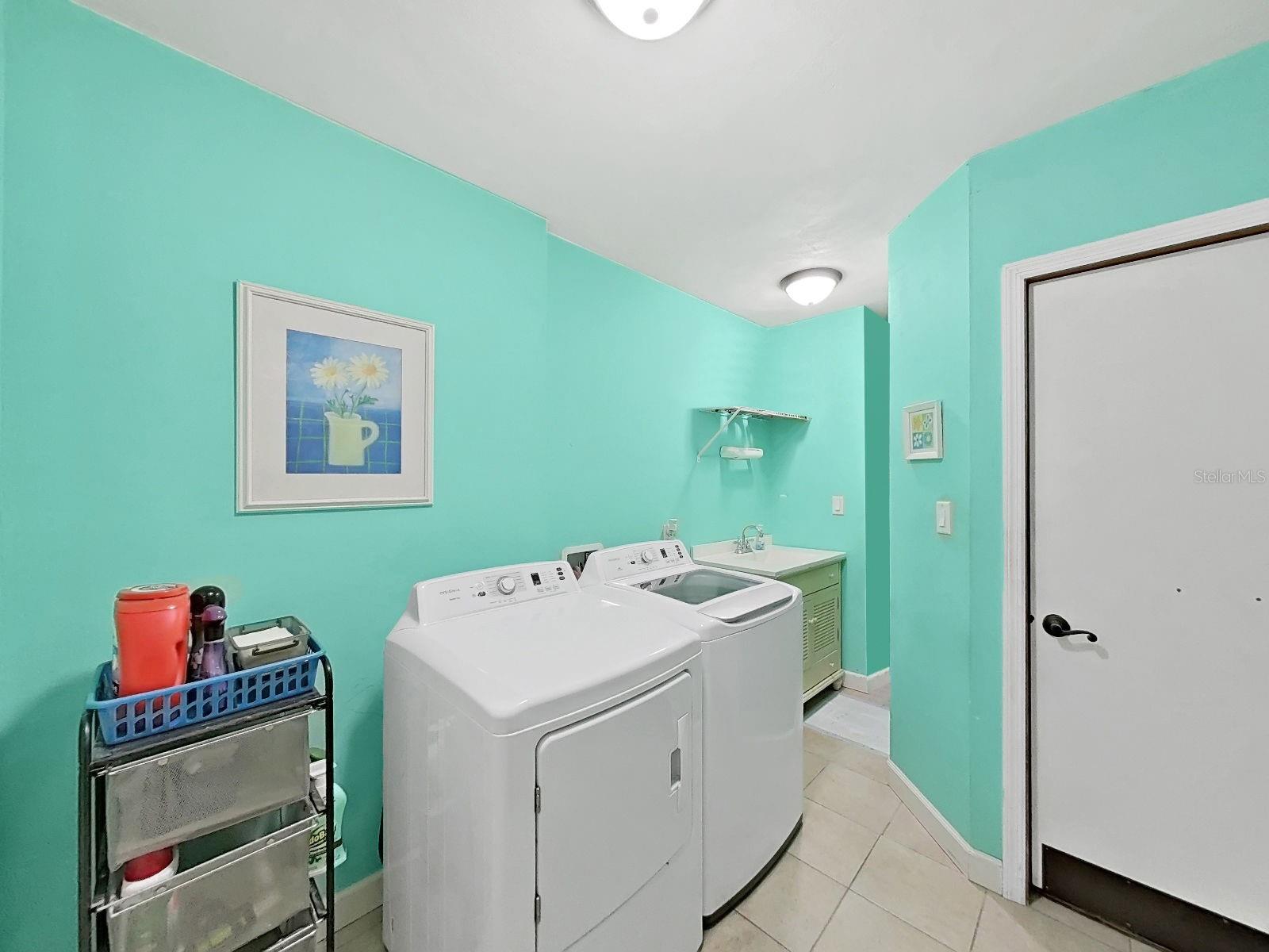 Bright & airy laundry room with integrated utility sink & vanity for storage.