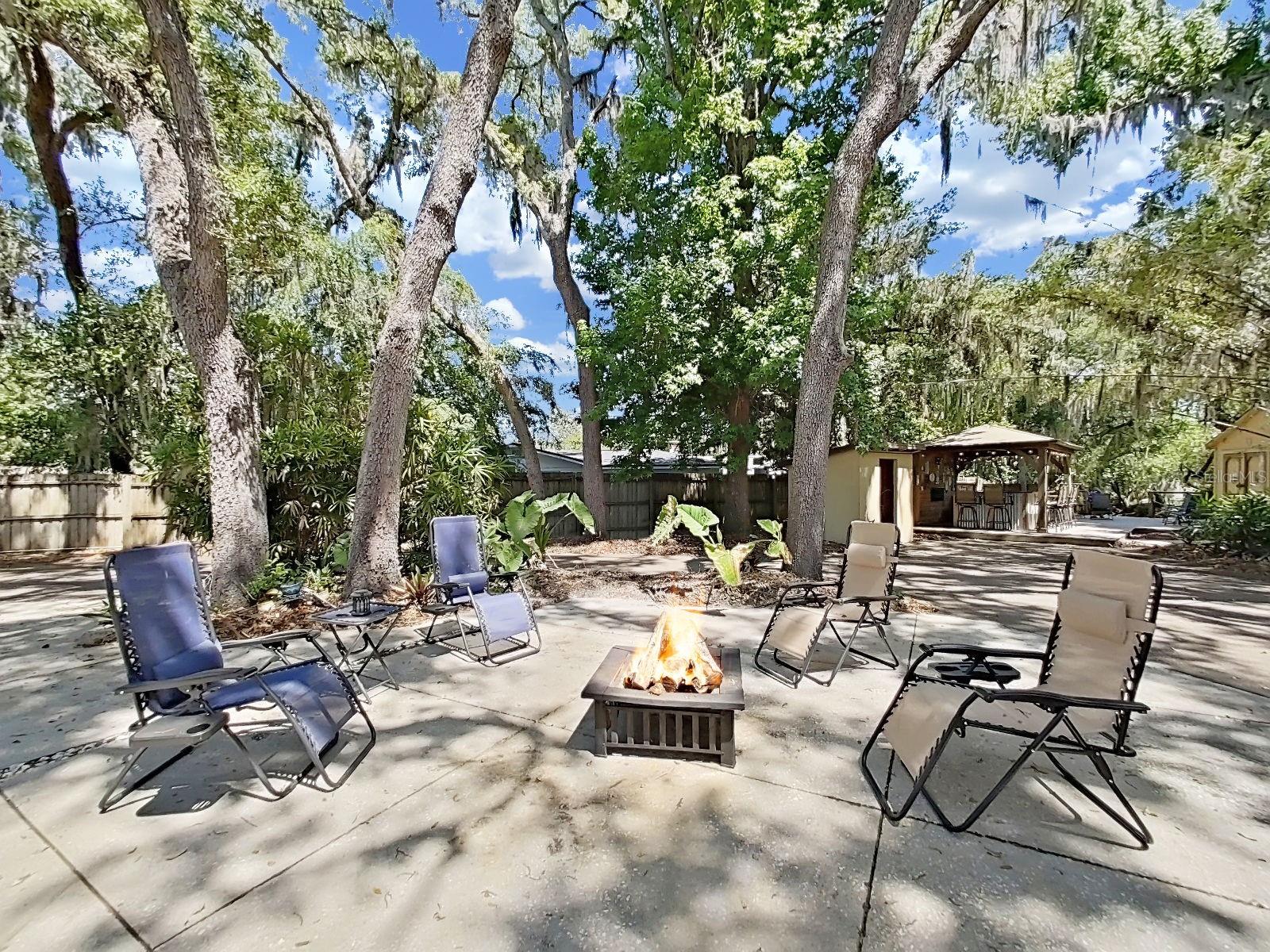 Backyard oasis with shaded areas by gorgeous mature trees, plus a gazebo bar in the background. Made for outdoor gatherings!