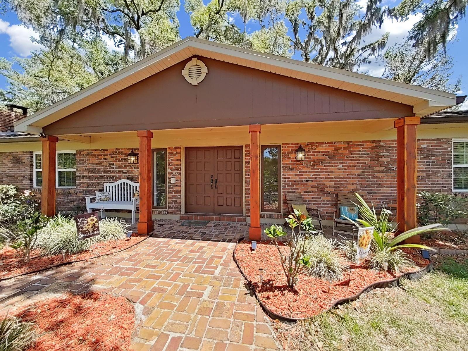 Grand covered front entry with solid double doors, brick paver walkway, wood beam columns & lush landscape. First impressions that truly deliver!