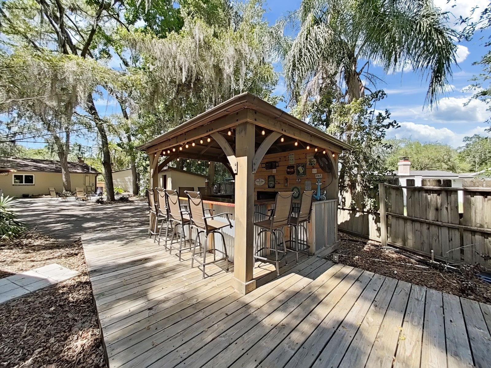 Outdoor bar filled with Florida charm! String lights, bar seating, & wrap around deck- designed for entertaining under the Florida sky!