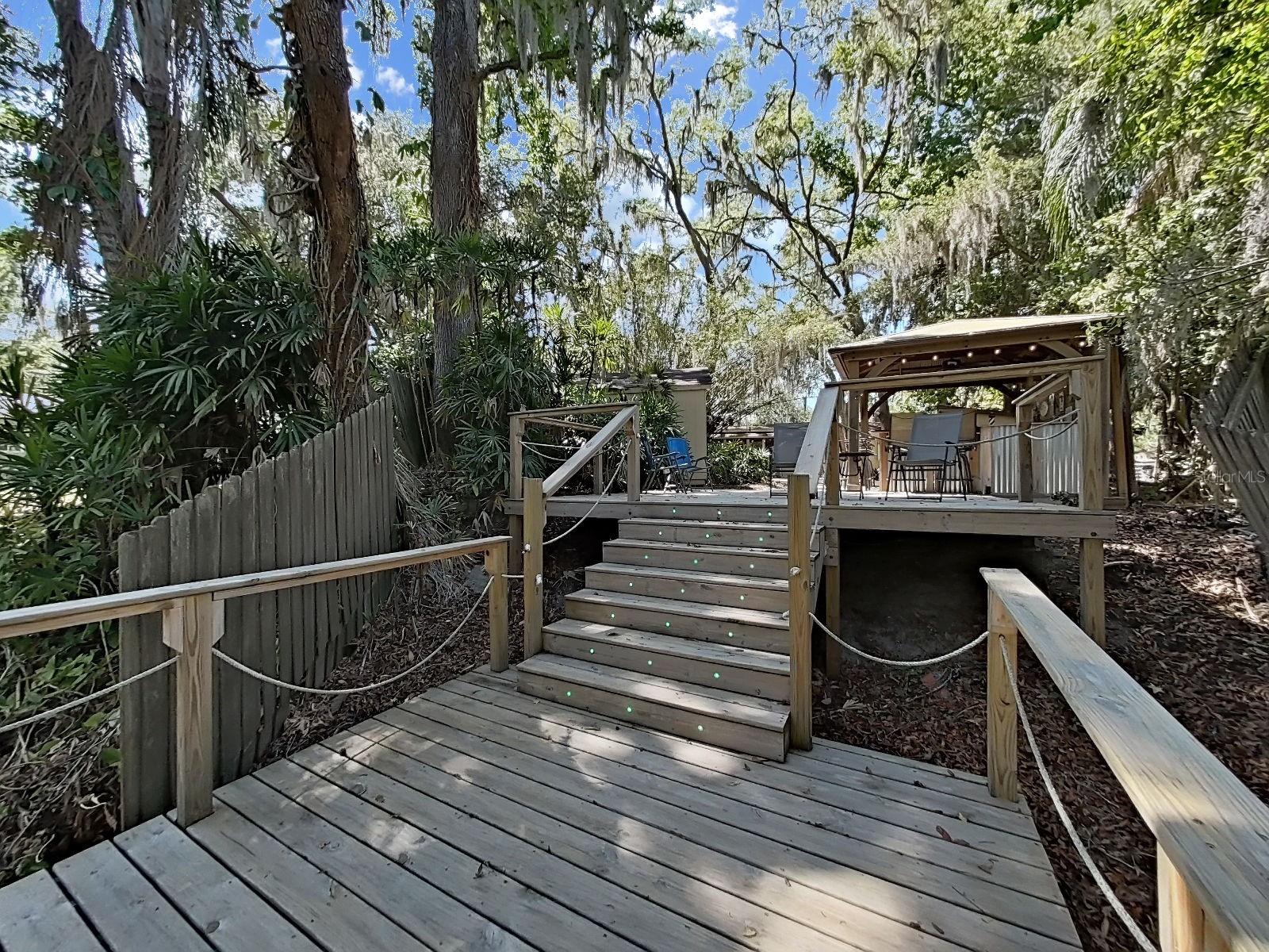Multi-level deck and dock with lighted stair risers and rope railings, leading to the outdoor bar gazebo. A resort-like backyard experience unlike any other.