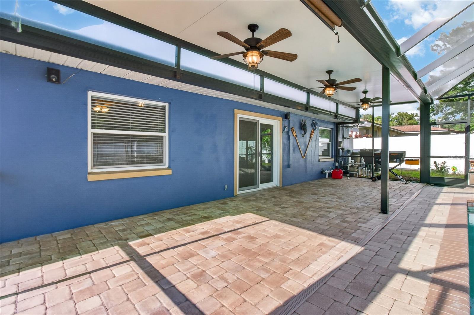 Covered patio area with paver flooring provides extra space to entertain next to the pool.