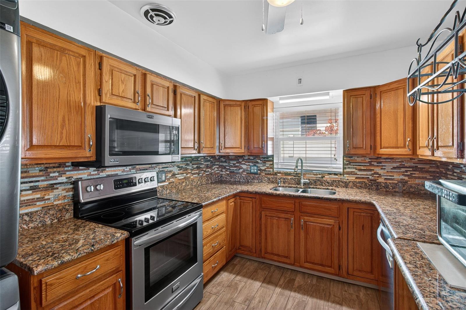 Kitchen has solid wood cabinets, granite countertops, decorative tile backsplash, tile floors