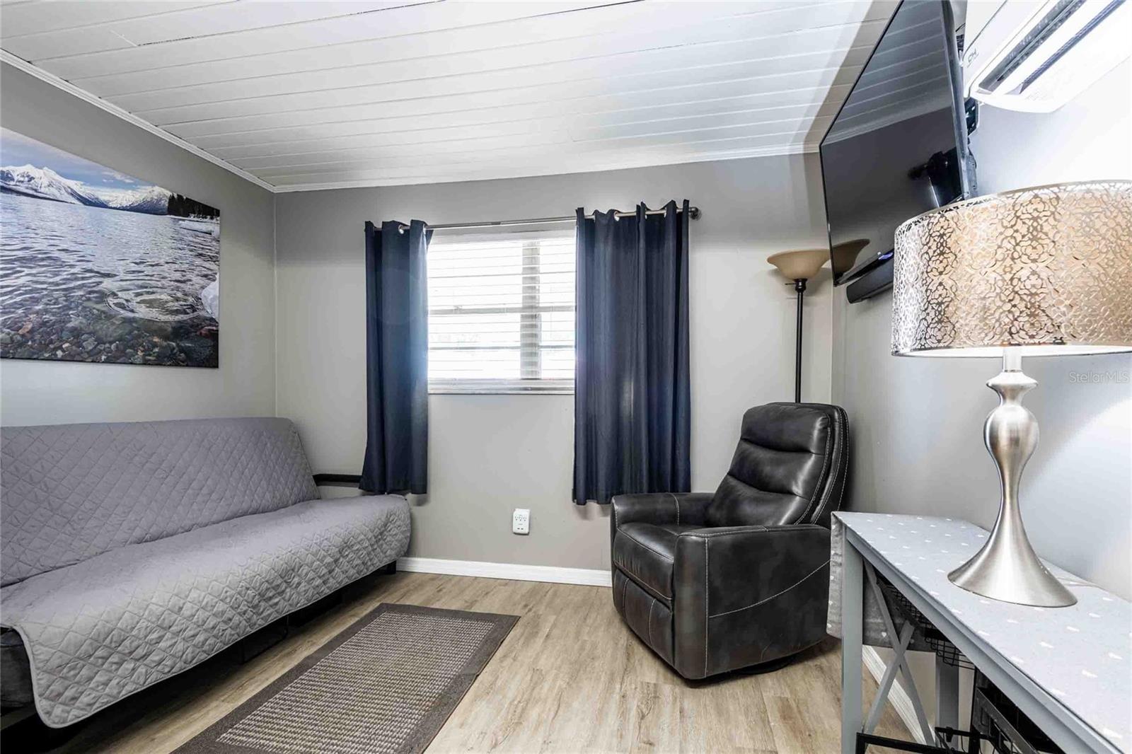 A futon can be converted to a bed and there is a closet next to the futon.