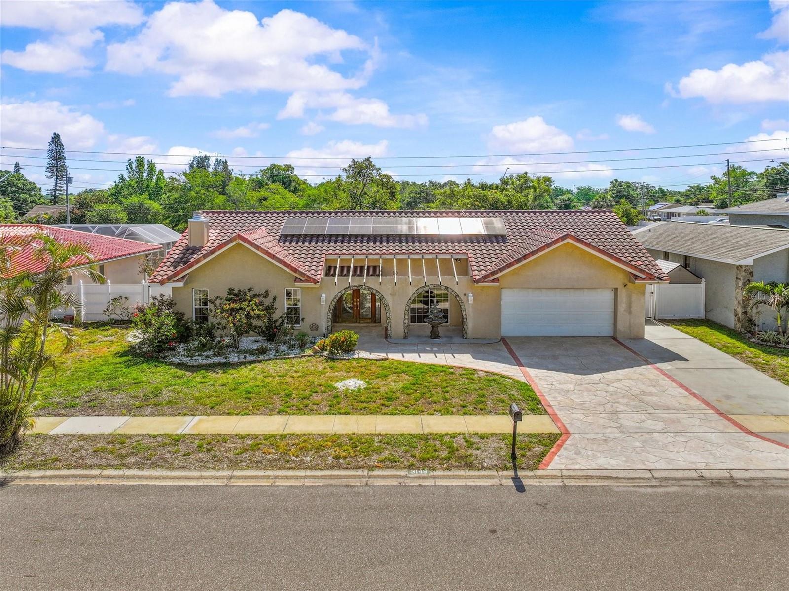 Aerial perspective highlights the home’s modern solar tile roof and prime Dunedin location—just minutes from vibrant downtown, waterfront parks, and the Pinellas Trail.