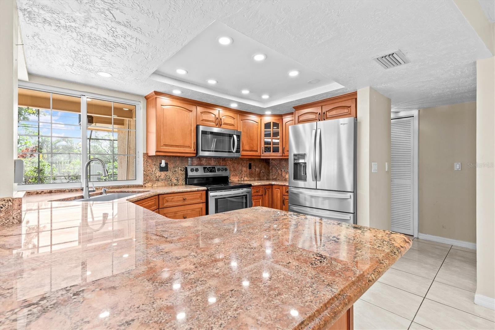 Kitchen with granite countertops and pool views through oversized windows.