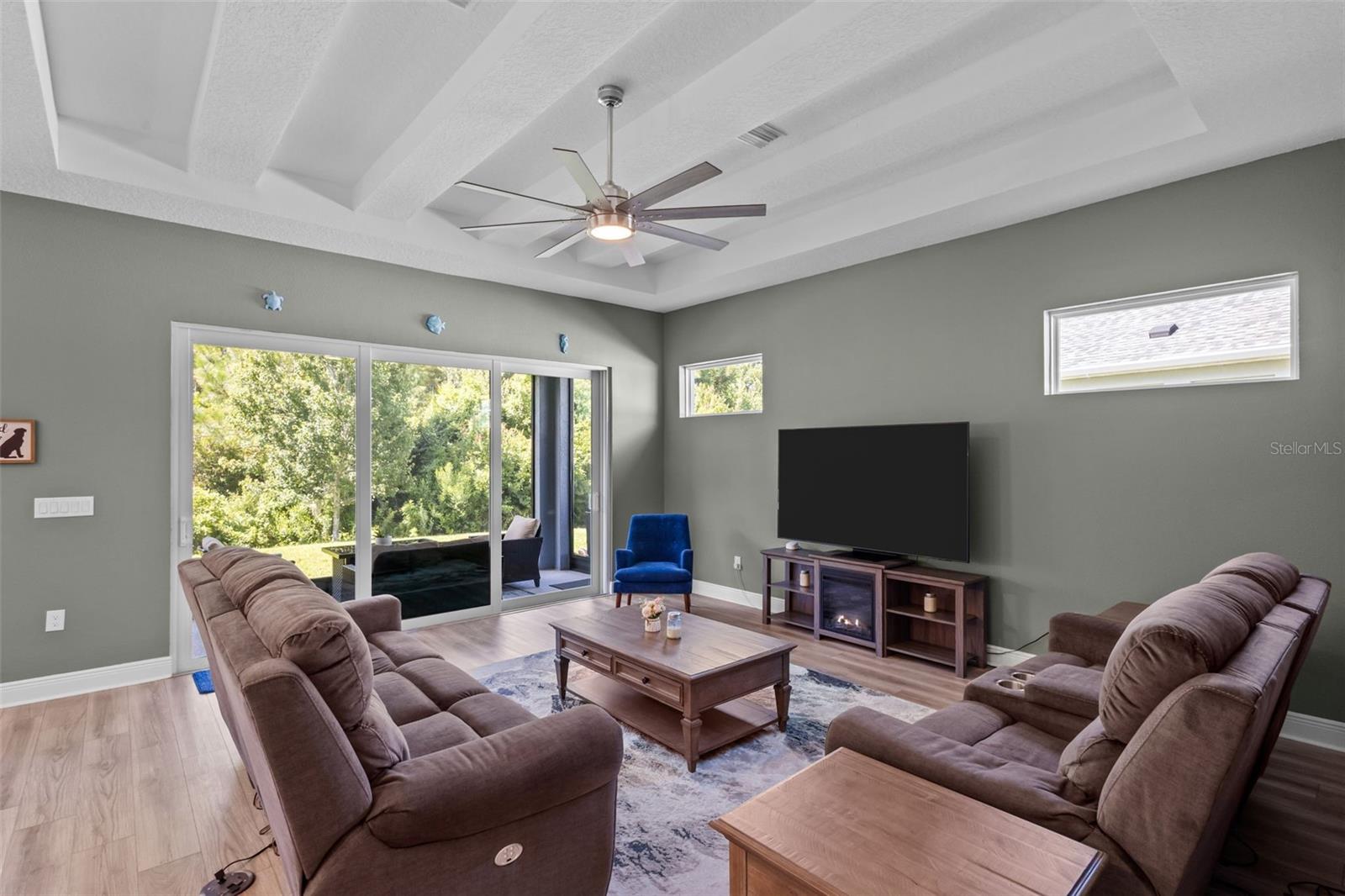 Spacious living room with high ceilings, tray detail, and decorative beam accents.