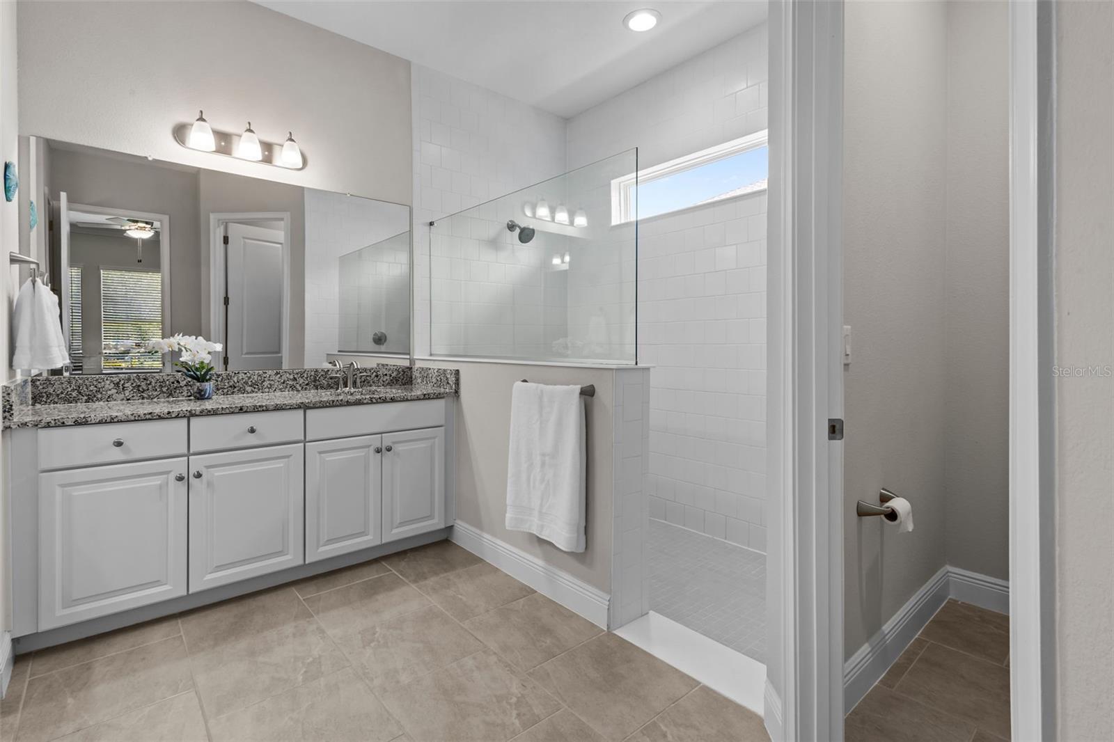 Primary bathroom with dual vanities and a large walk-in shower.