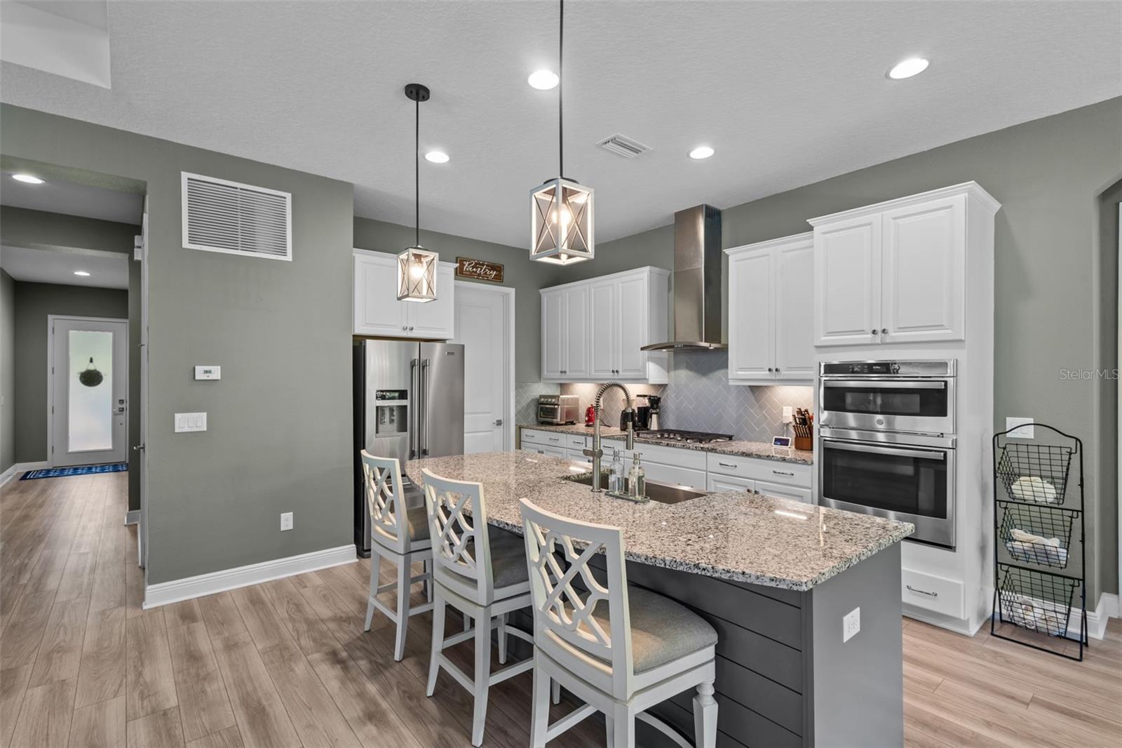 Natural gas cooktop, built-in oven, vent hood, and herringbone backsplash complete the kitchen.