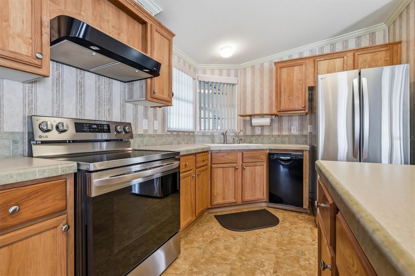 Kitchen features a Corian island top that seats 4, a Corian tiled countertop,  a refrigerator with ice maker & water, a Culligan RO system at the sink for water, and a stove with a convection oven feature