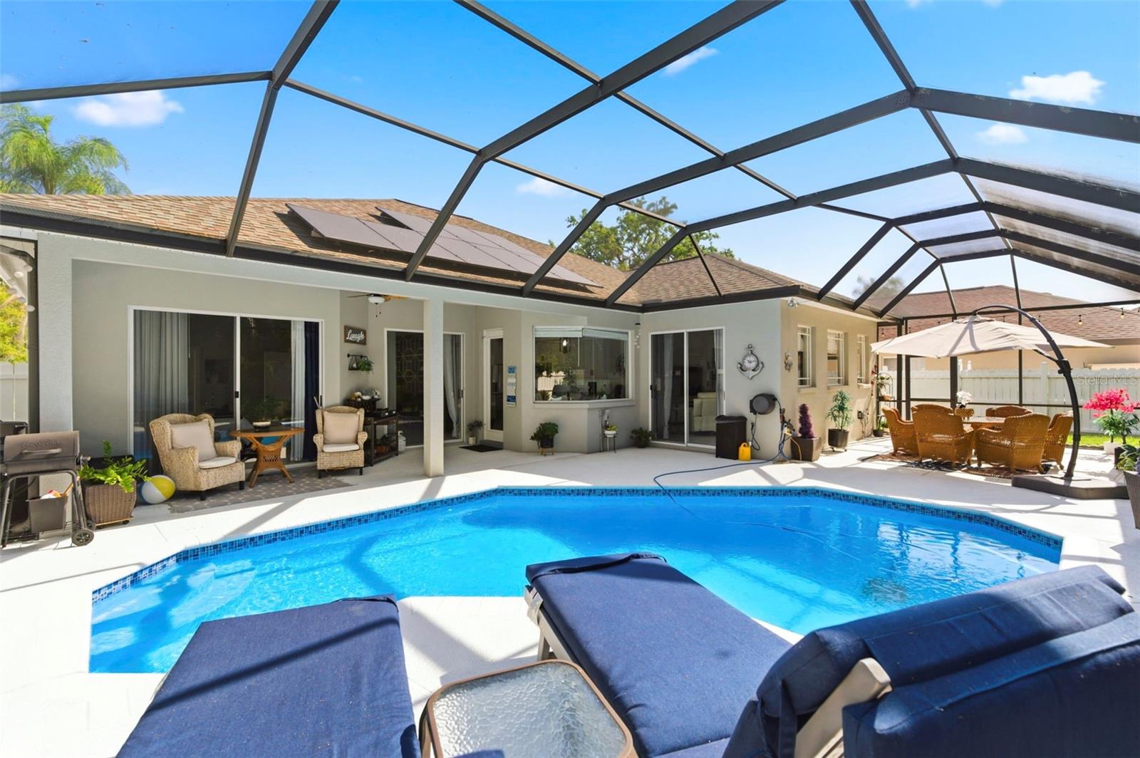 Resort-style screened-in pool area offering the perfect private outdoor retreat. Enjoy a sparkling pool surrounded by an expansive patio with ample space for lounging and entertaining. The covered lanai provides shaded seating, while sliding glass doors create seamless indoor-outdoor living. Lush landscaping and a fully fenced yard add privacy, making this space ideal for relaxing or hosting guests year-round.