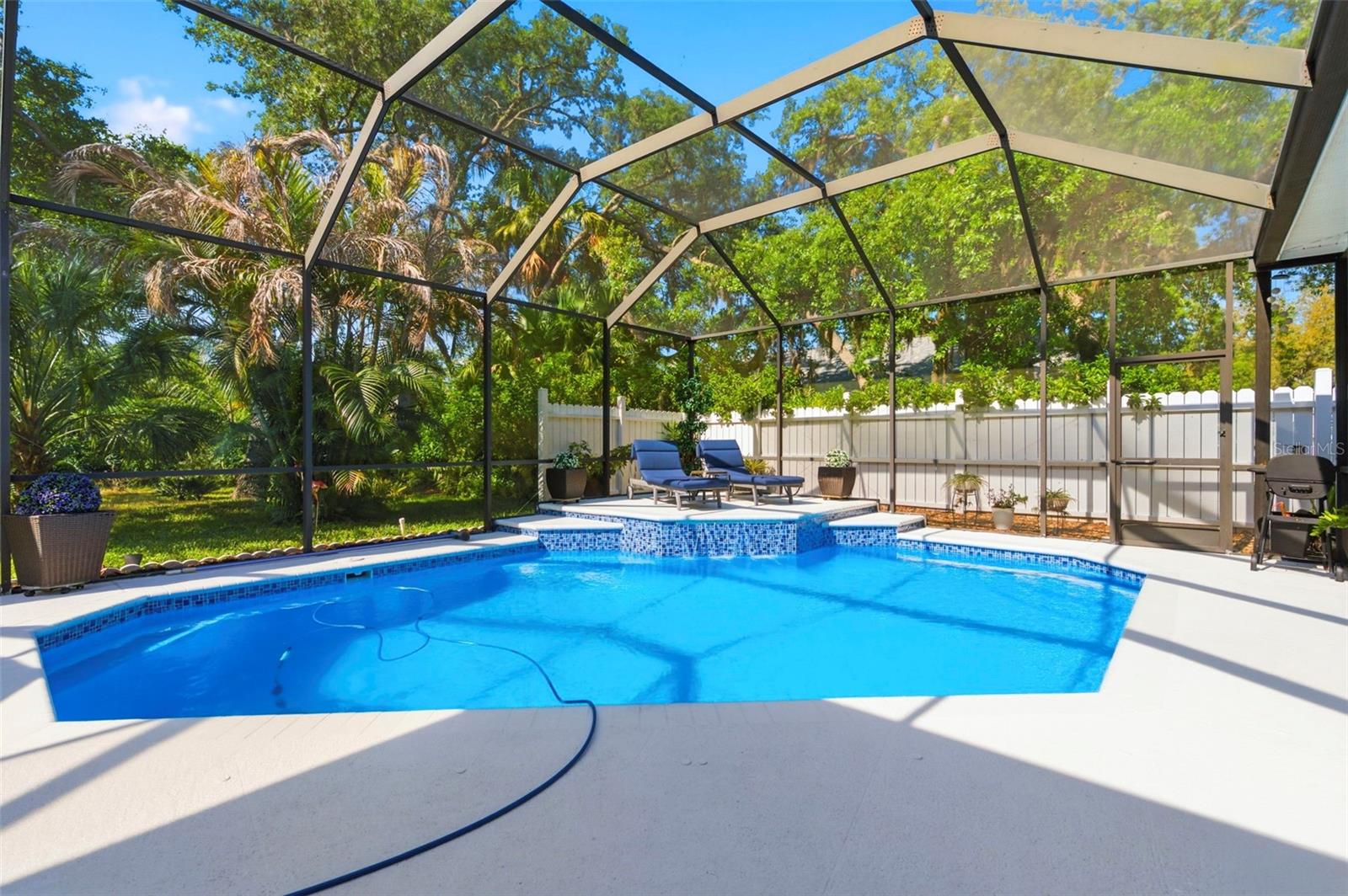 Resort-style screened-in pool area offering the perfect private outdoor retreat. Enjoy a sparkling pool surrounded by an expansive patio with ample space for lounging and entertaining. The covered lanai provides shaded seating, while sliding glass doors create seamless indoor-outdoor living. Lush landscaping and a fully fenced yard add privacy, making this space ideal for relaxing or hosting guests year-round.