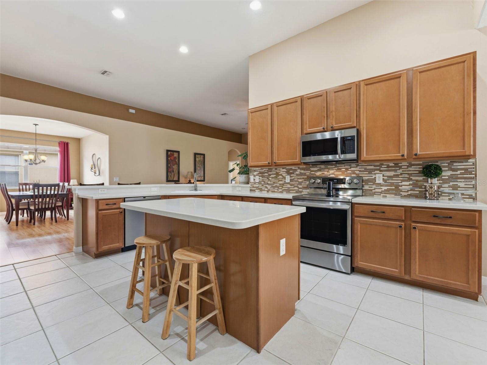 Tiled backsplash, stainless steel appliances, 42" wood cabinets and gleaming white solid surface counters