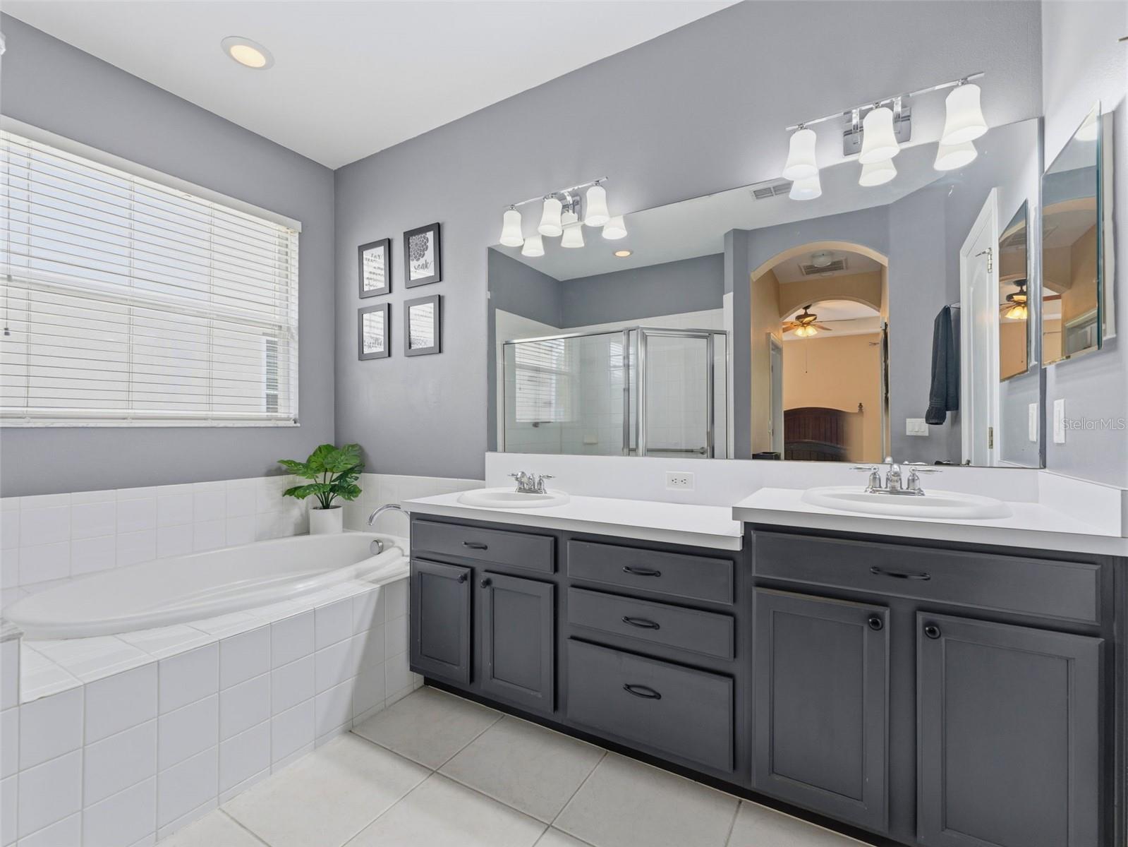 Primary bath features garden tub, dual sinks, and large shower with glass enclosure; private water closet too