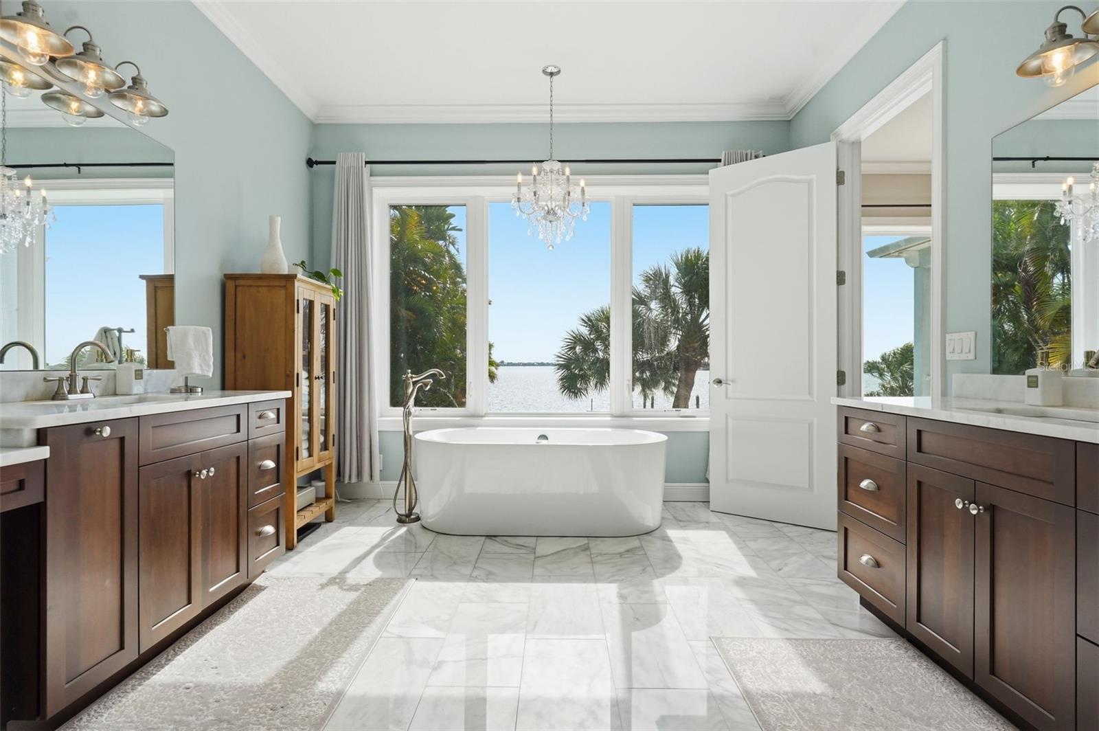 Master bedroom bedroom suite's bathroom offers a tub with a sparkling chandelier and a spectacular water view. All the marble is nice, too.