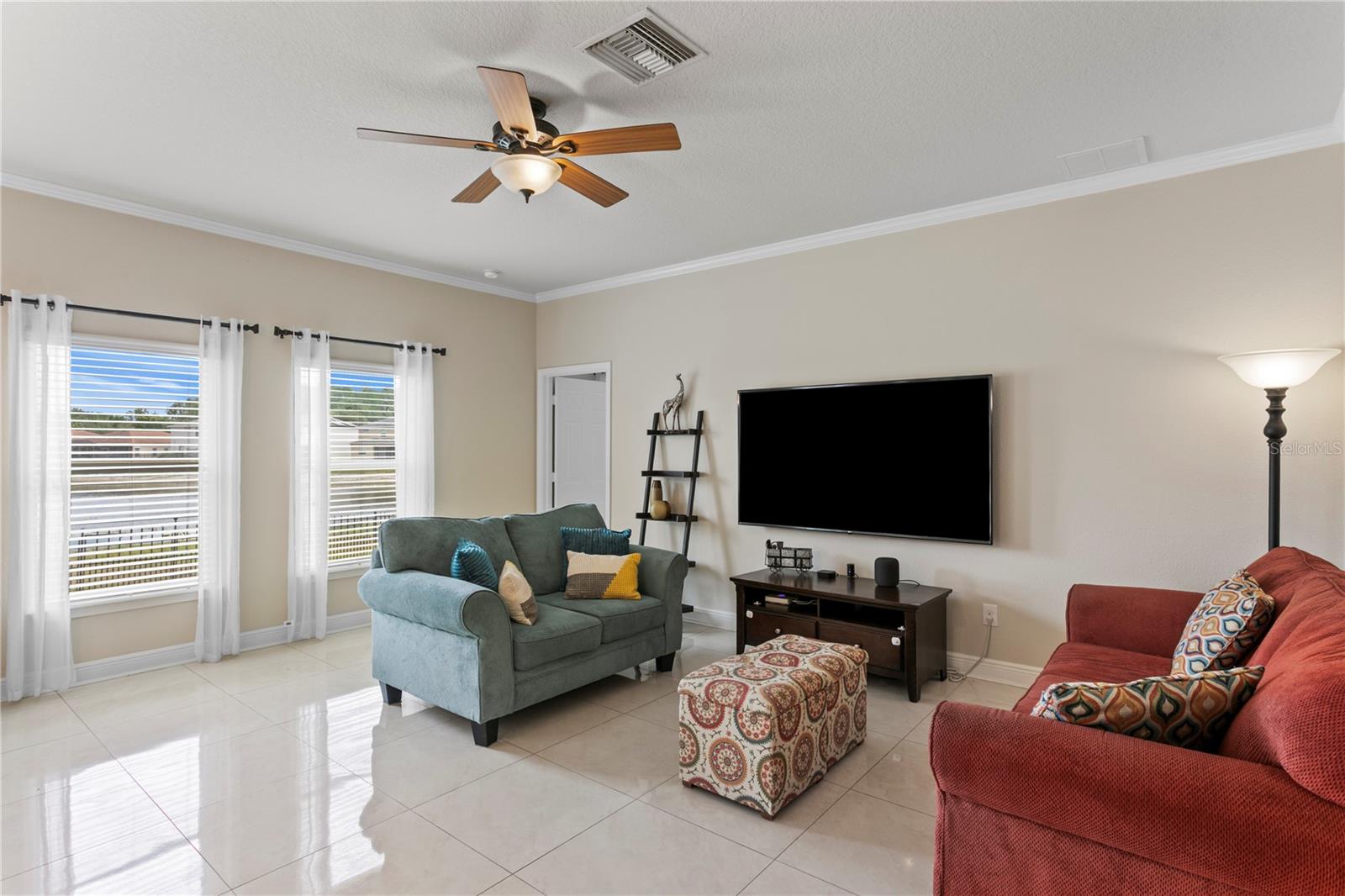 Family room features a ceiling fan and crown molding