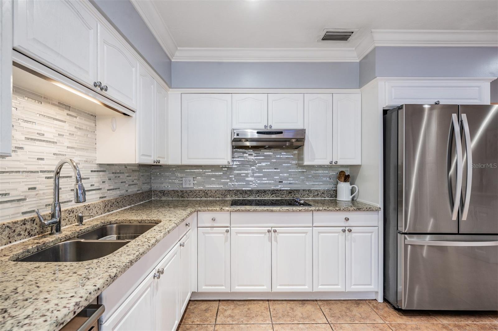 solid surface granite countertops in neutral tones, flat cooktop, Kenmore appliances, soft close cabinets with pull outs.