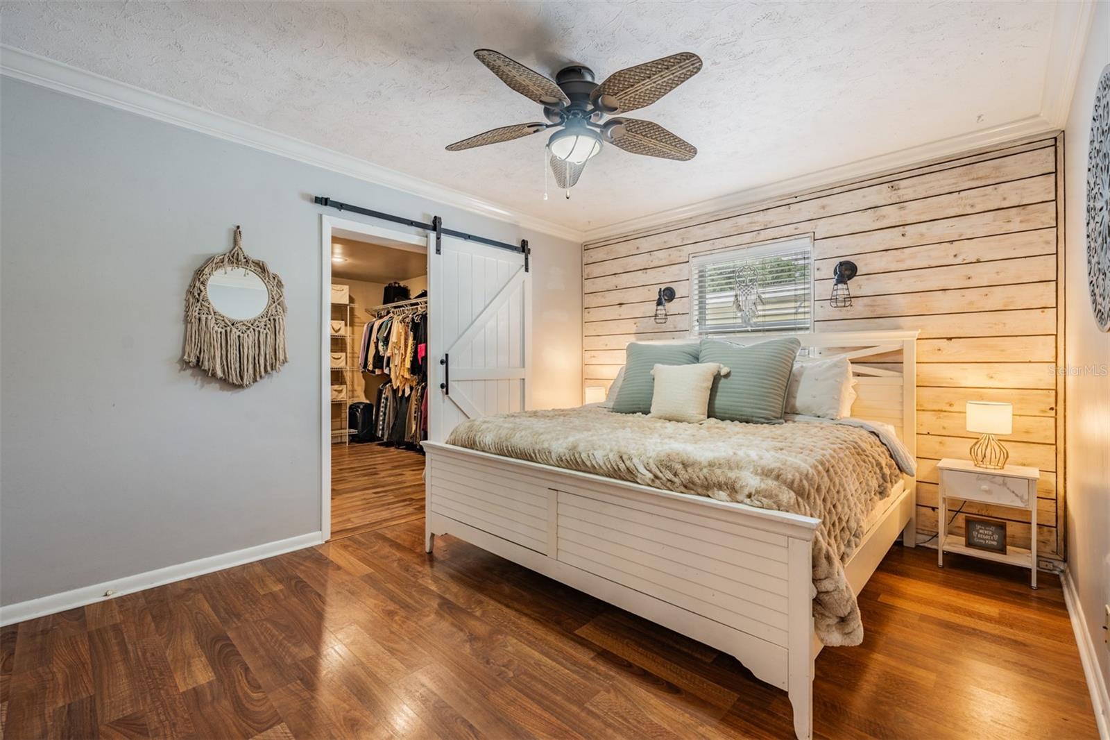 primary bedroom with shiplap accent wall and sliding door to the massive wardrobe closet