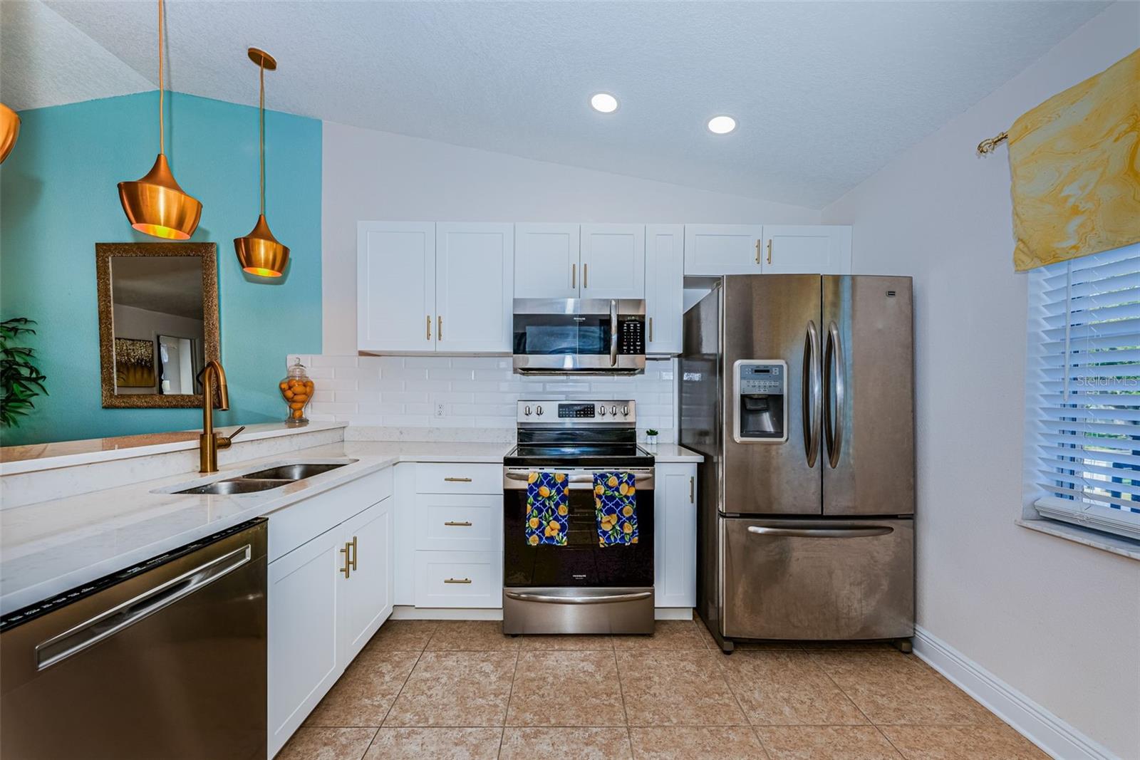 Updated Kitchen has recessed lighting, tile backsplash, Quartz countertops & newer Stainless Steel appliances, and opens to Living area.