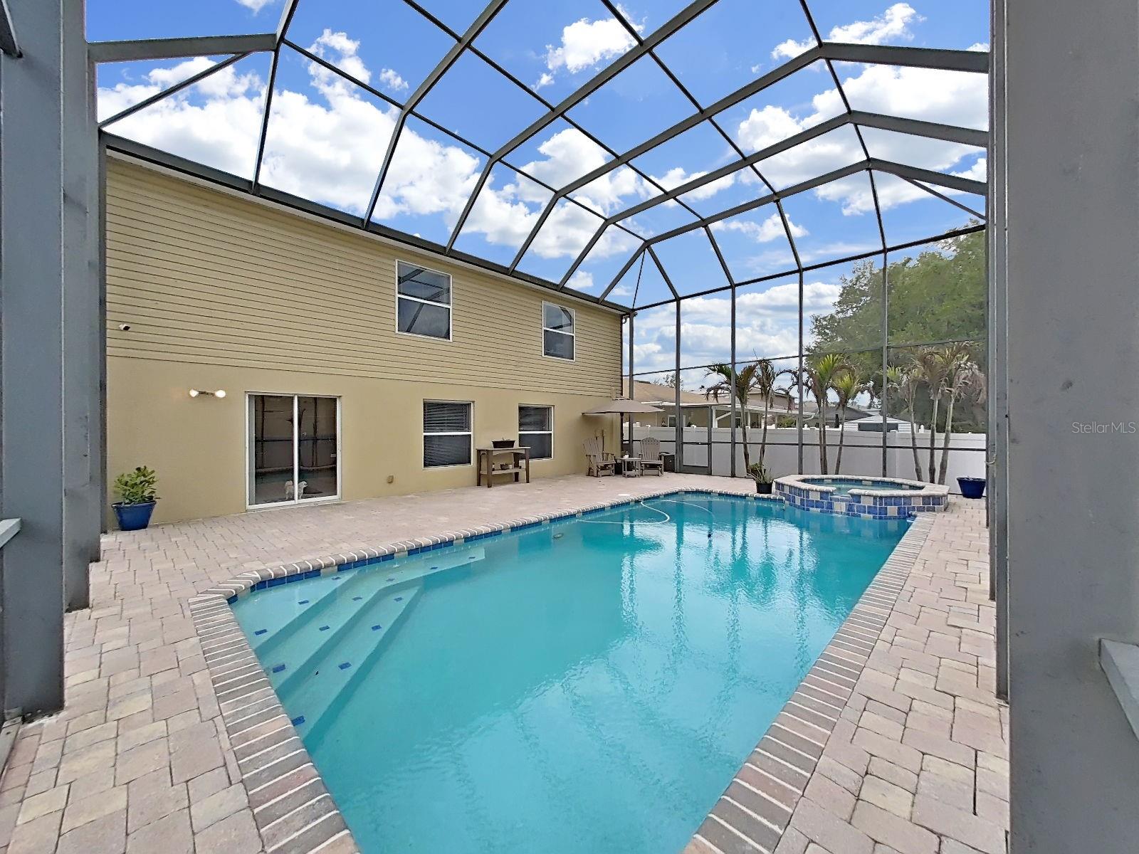 Shallow entry steps, sparkling blue water heated by solar panels, spillover spa and palm trees beyond. Newly screened pool cage. Jump in - the water's perfect!