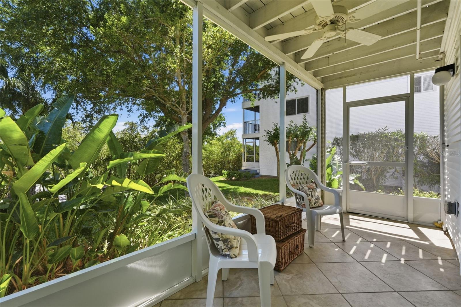 Side door of screened porch opens to concrete patio and green space to the dock.