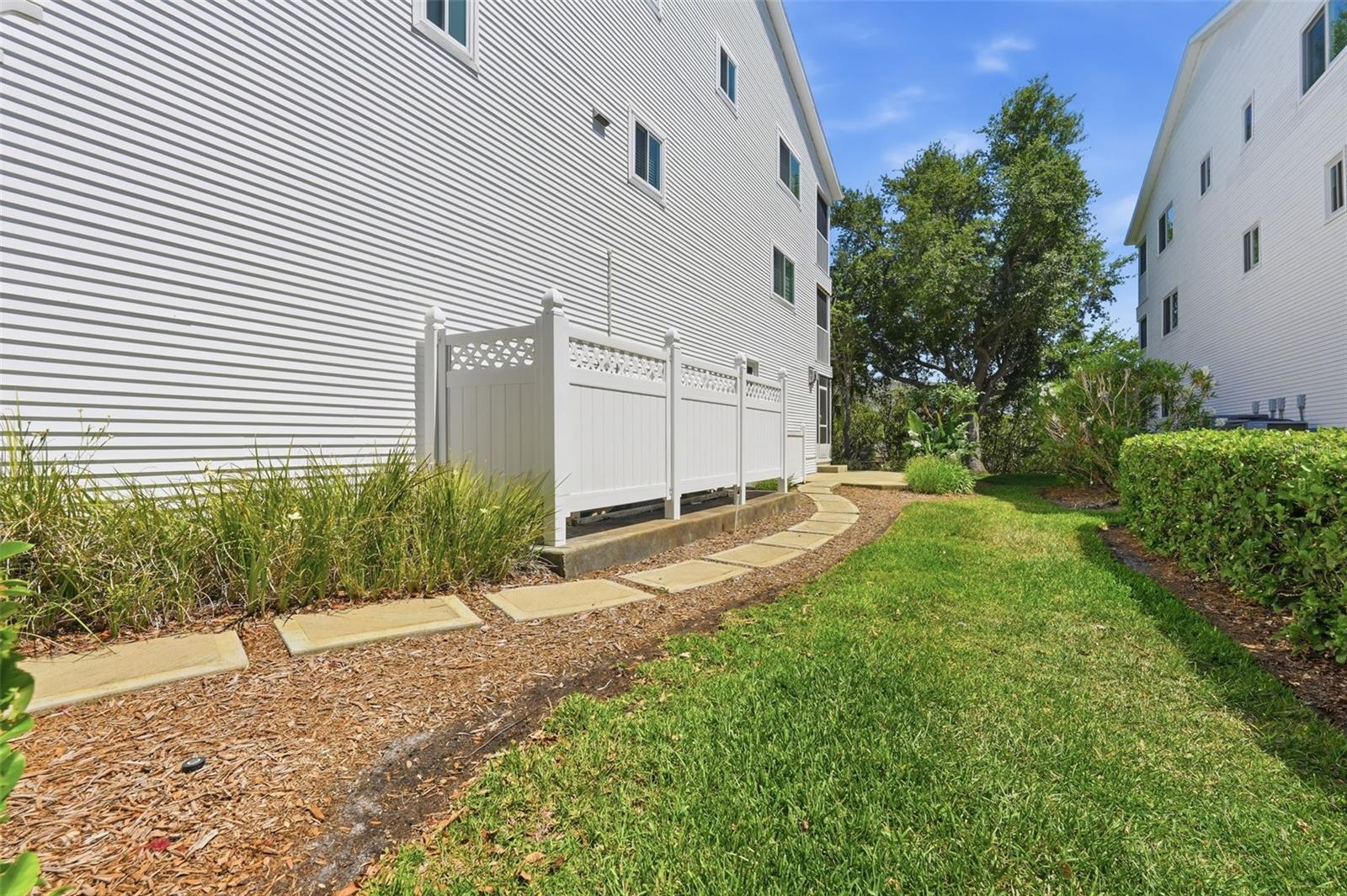 Concrete walkway from driveway to patio.  A/C is in the PVC fenced area and Propane tank for this townhome is just past the A/C
