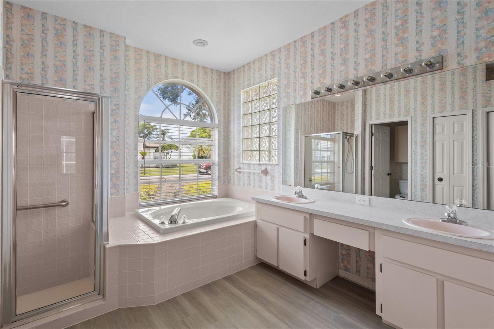 Primary bathroom with dual sinks, soaking tub, and separate shower.