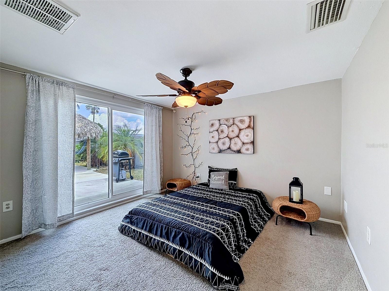 Bedroom 1 with sliding glass door to the paved patio and Tiki Hut
