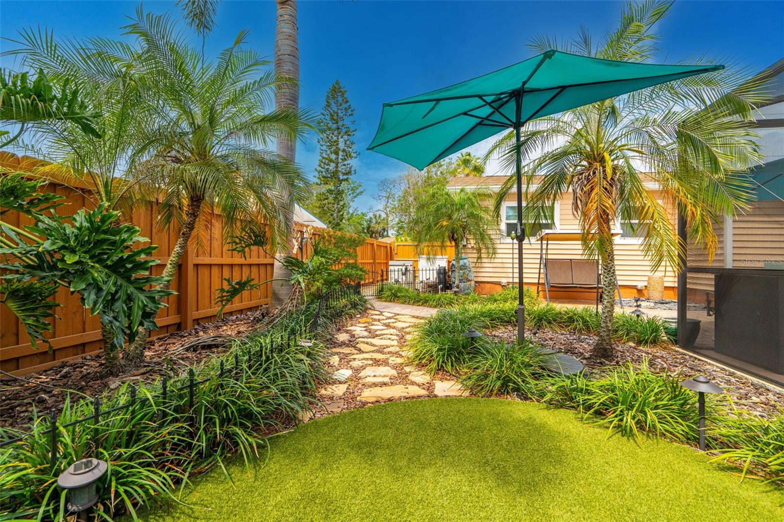 The grounds have been thoughtfully curated with pavered paths, multiple sitting areas, and lush tropical landscaping.