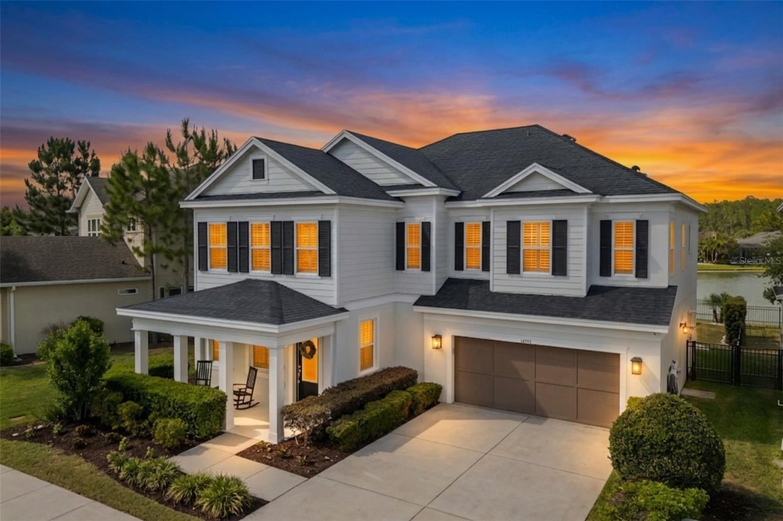 Pond-front home in Asturia with a screened lanai, gas-heated pool, and infinity-edge spa. Classic white exterior with black shutters, thoughtfully upgraded interior finishes, and a layout designed for both everyday living and entertaining